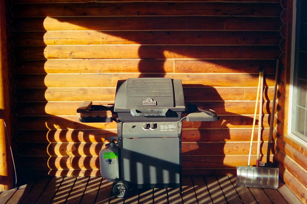 Gas grill sitting on a wooden deck, ready for summer cooking