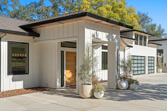 Modern white house with glass garage doors and plants