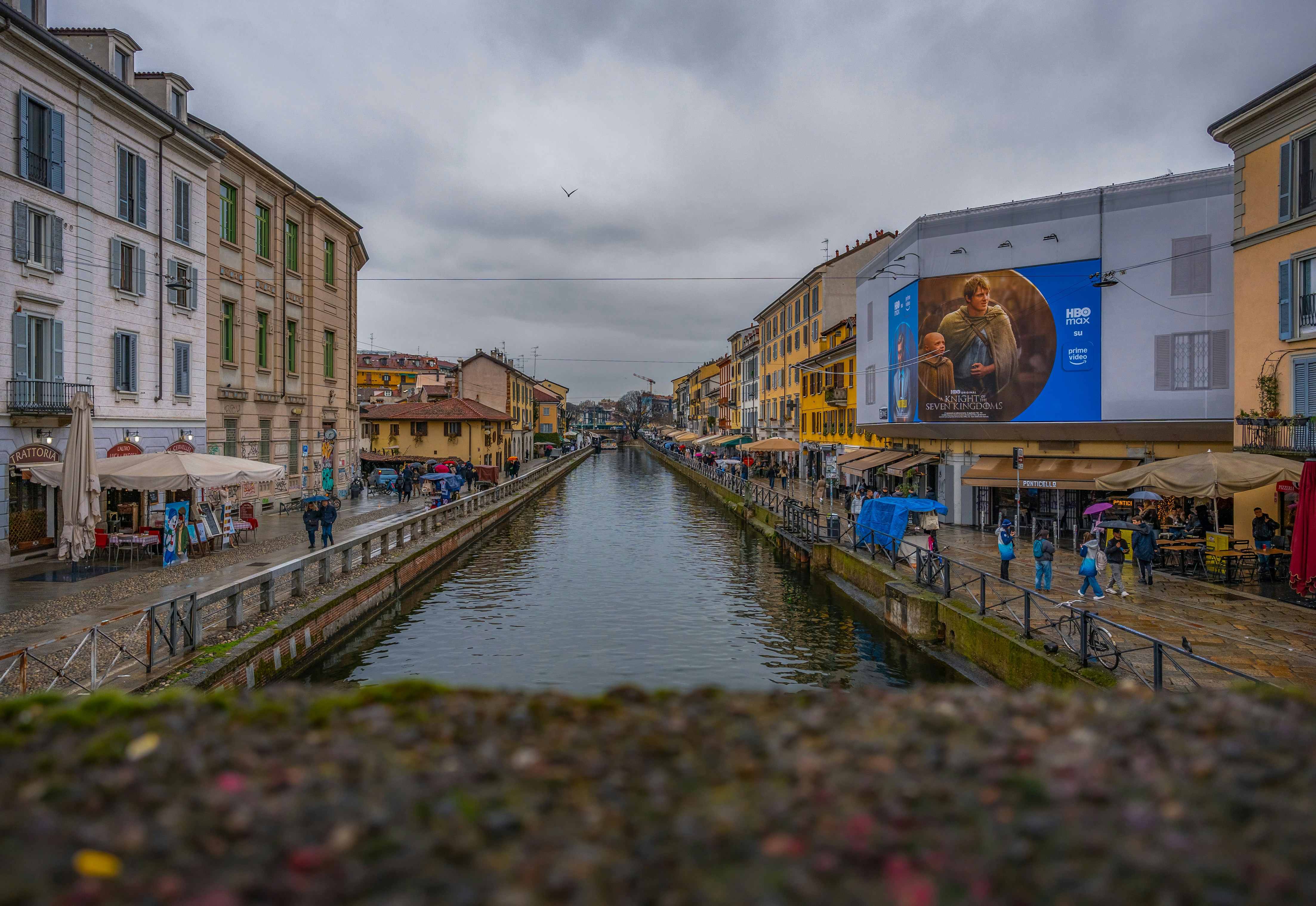 Canal with buildings and umbrellas on a cloudy day.