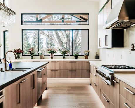 Modern kitchen with wood cabinets and large windows.