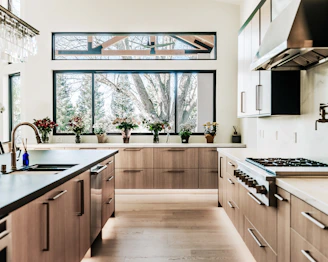 Modern kitchen with wood cabinets and large windows.