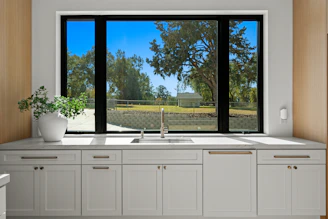 Kitchen sink and cabinets with a large window view.