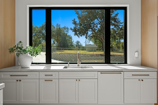 Kitchen sink and cabinets with a large window view.