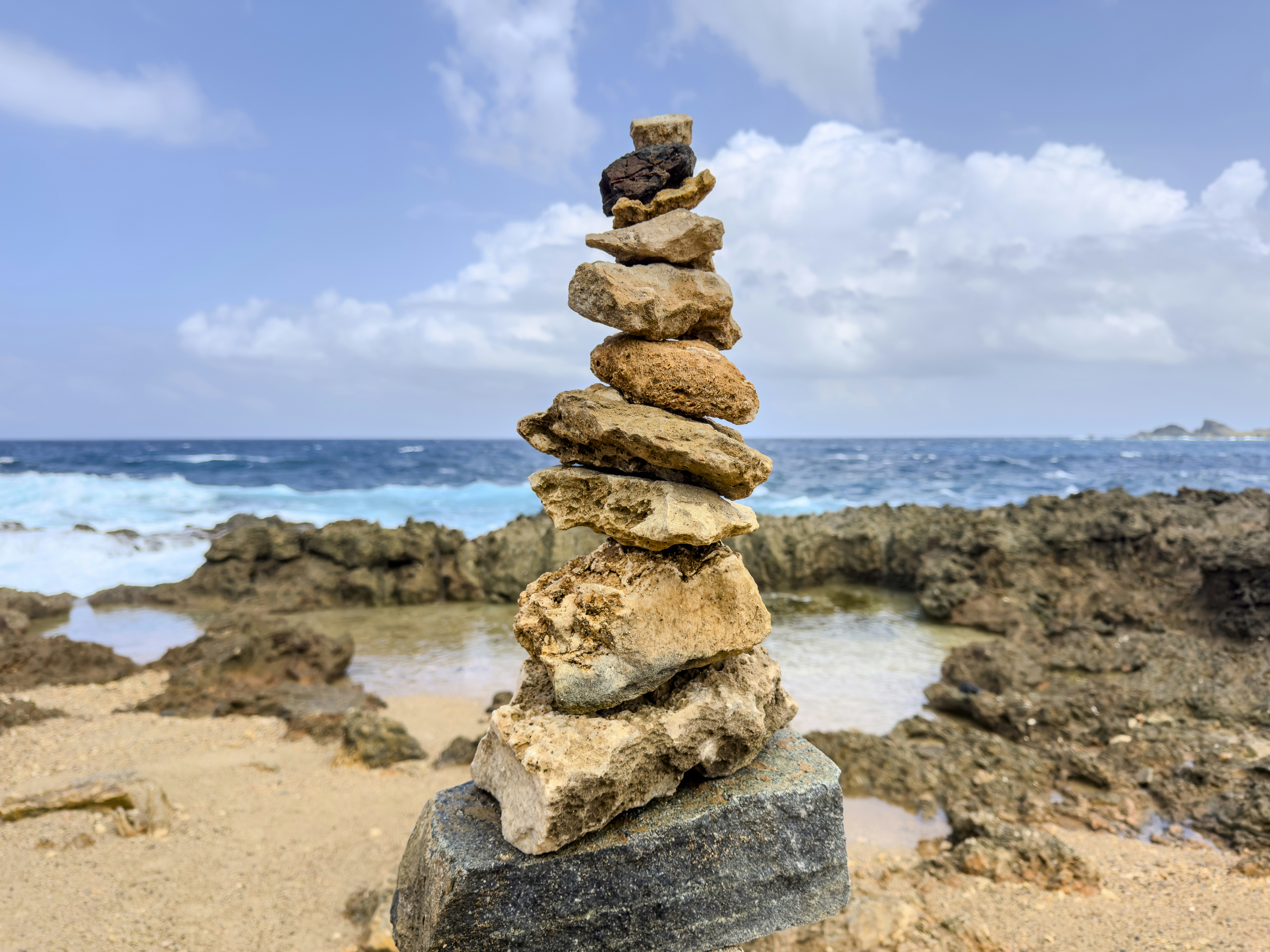 Ein Steinestapel an einem felsigen Strand mit Meereswellen.