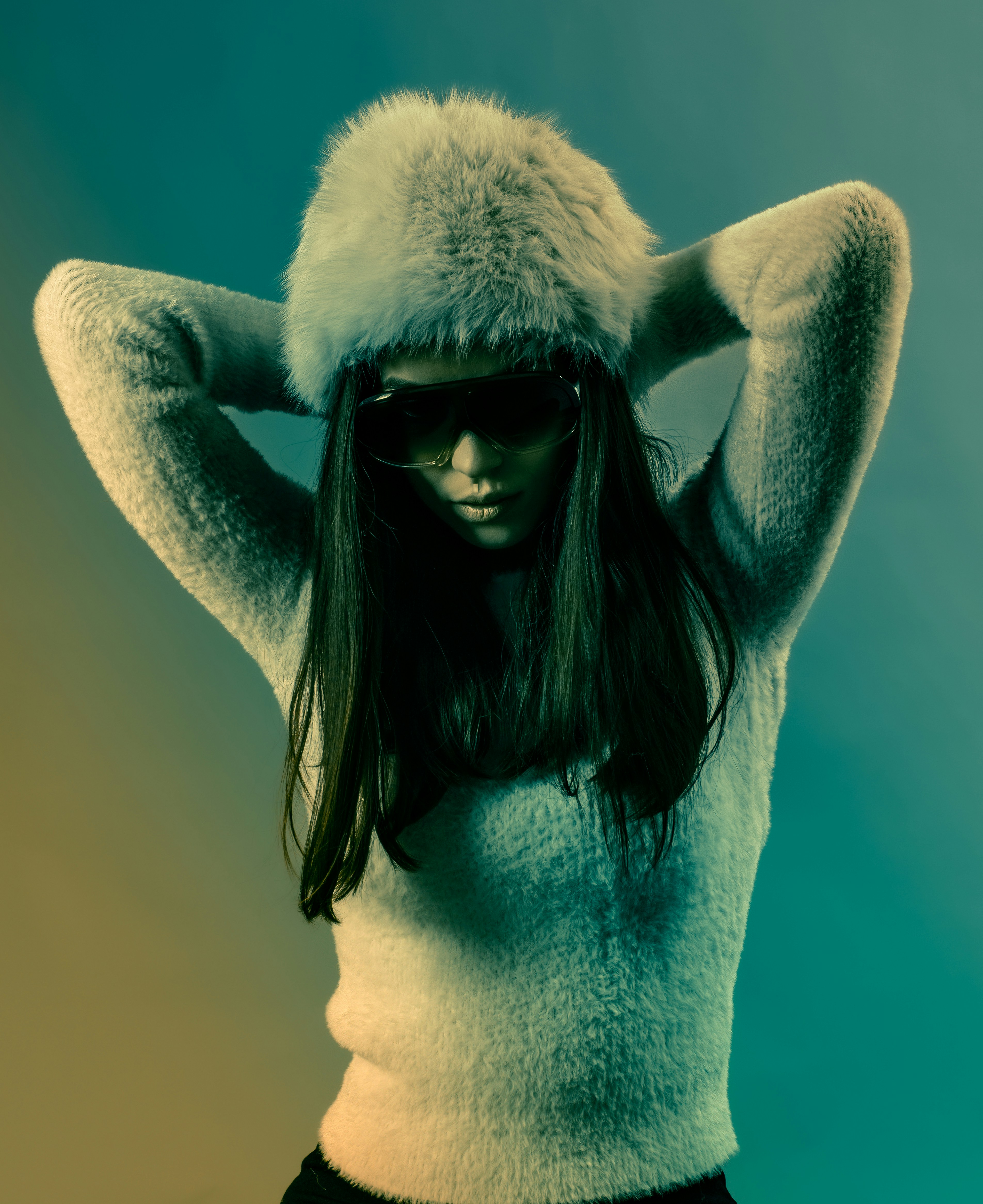 Femme au chapeau duveteux et lunettes de soleil, les mains derrière la tête