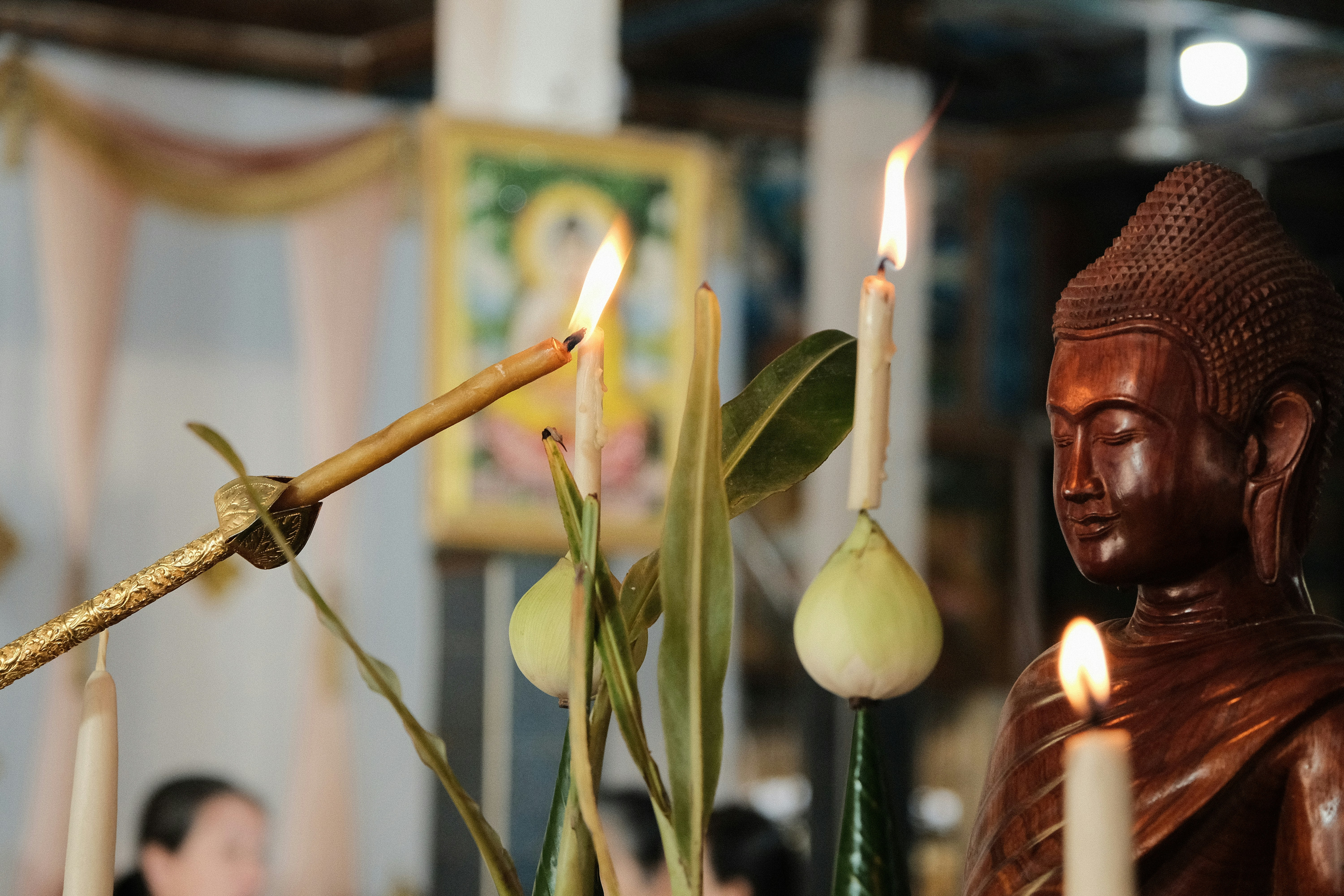A wooden buddha statue with lit candles and offerings.