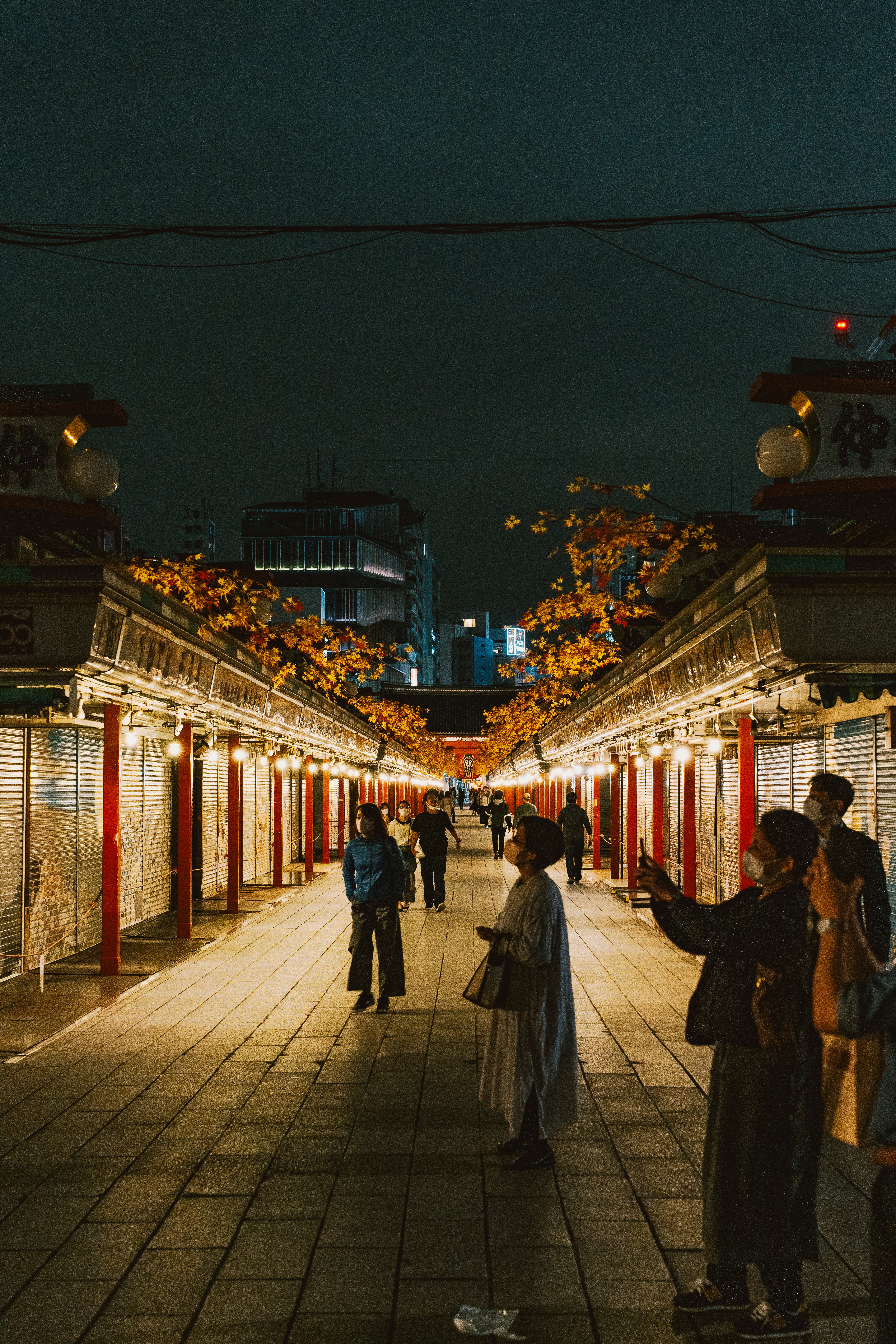 People walking through a brightly lit market at night.