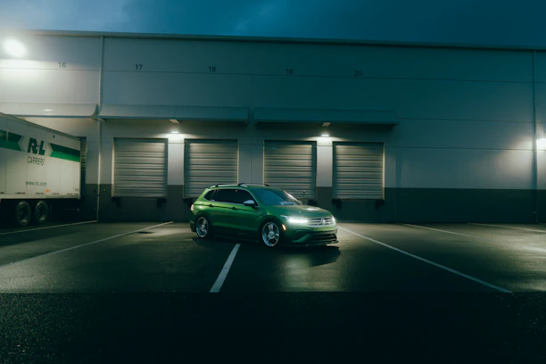 Green car parked outside warehouse at night