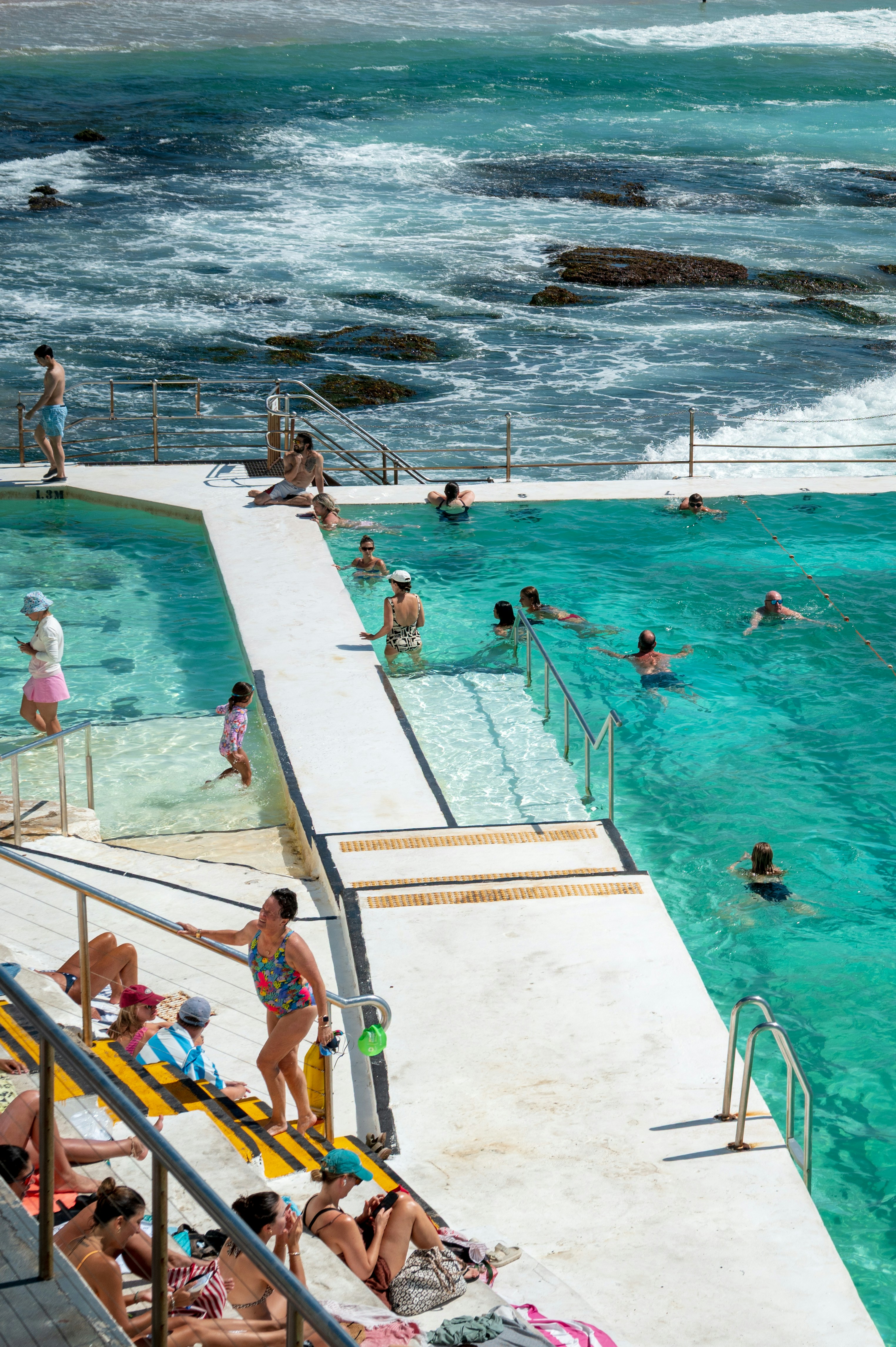 Le persone nuotano e si rilassano in una piscina oceanica soleggiata.