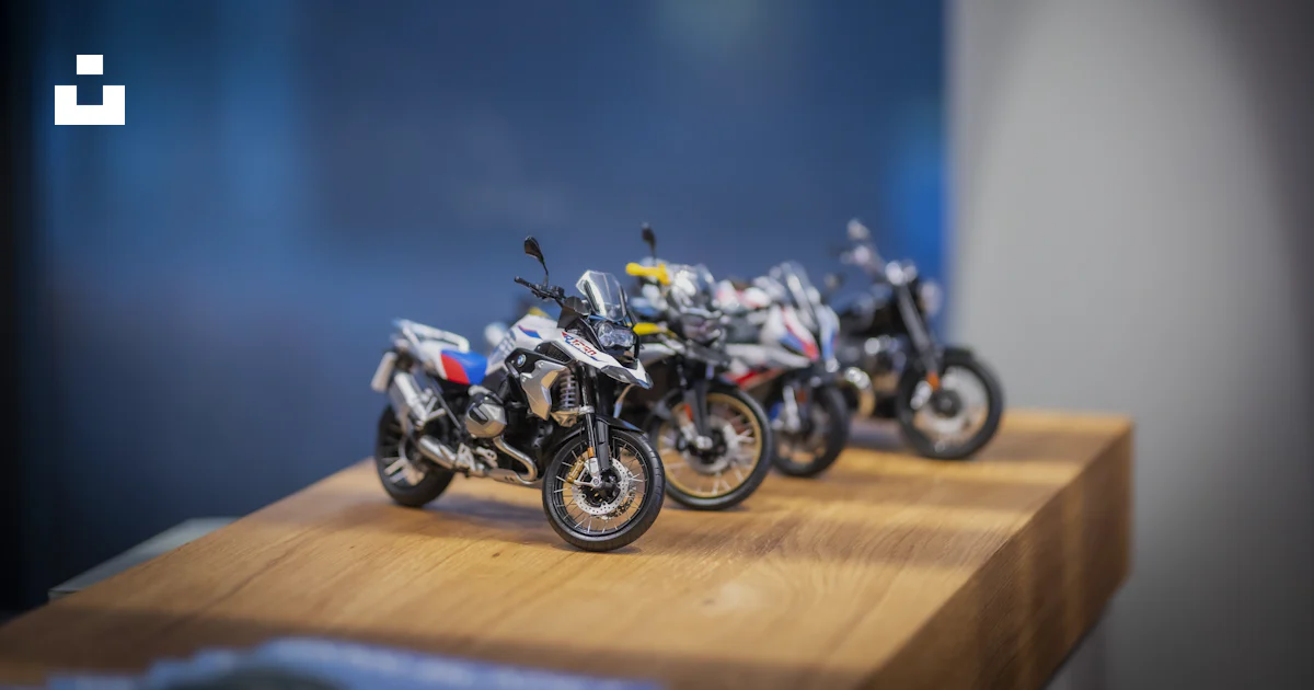 Ministation Motorcycle Model Three miniature motorcycles displayed on a wooden surface. photo – Free ...