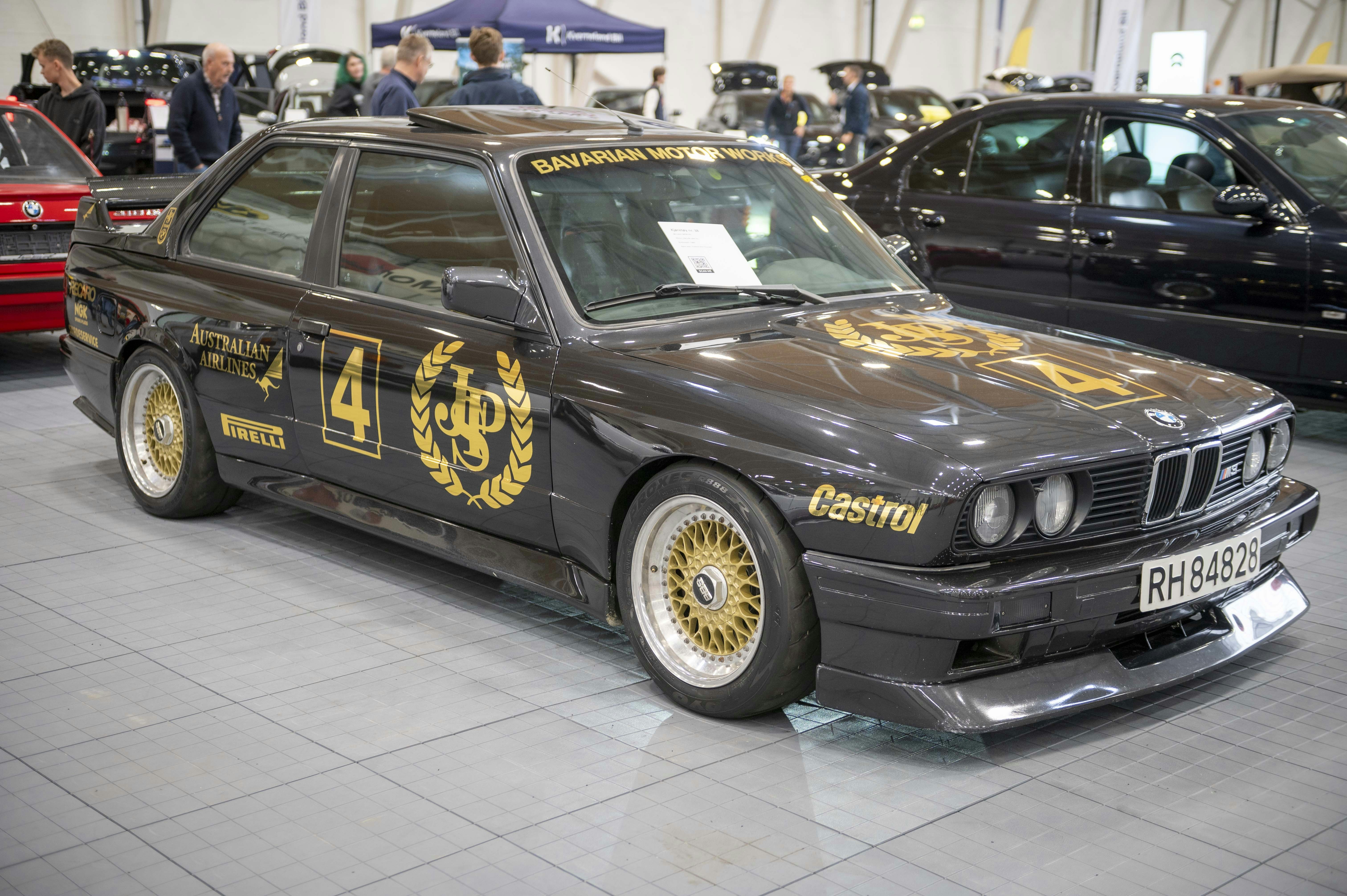 A customized dark gray BMW m3 with gold racing decals