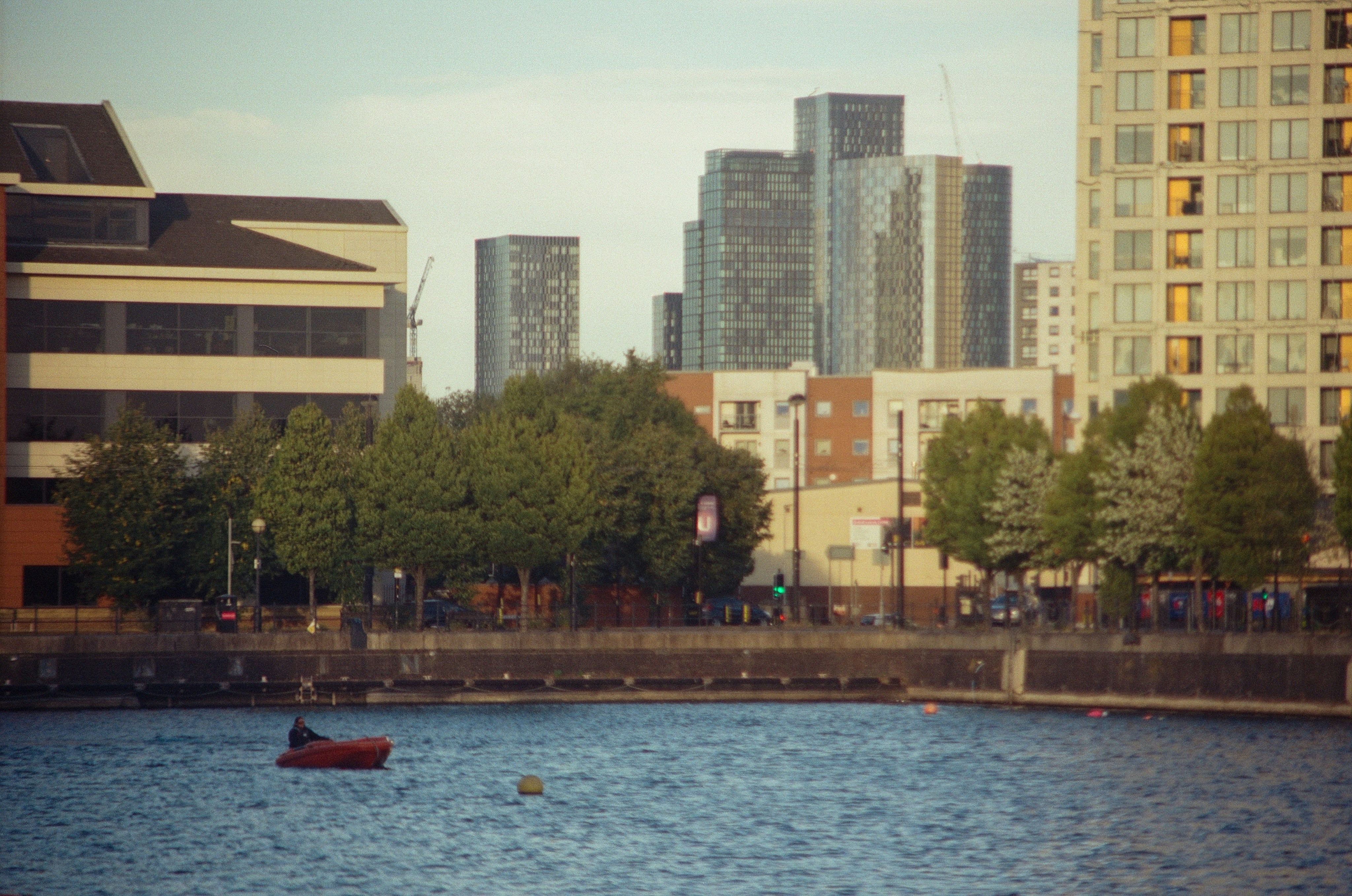 City skyline with modern buildings and trees by water.