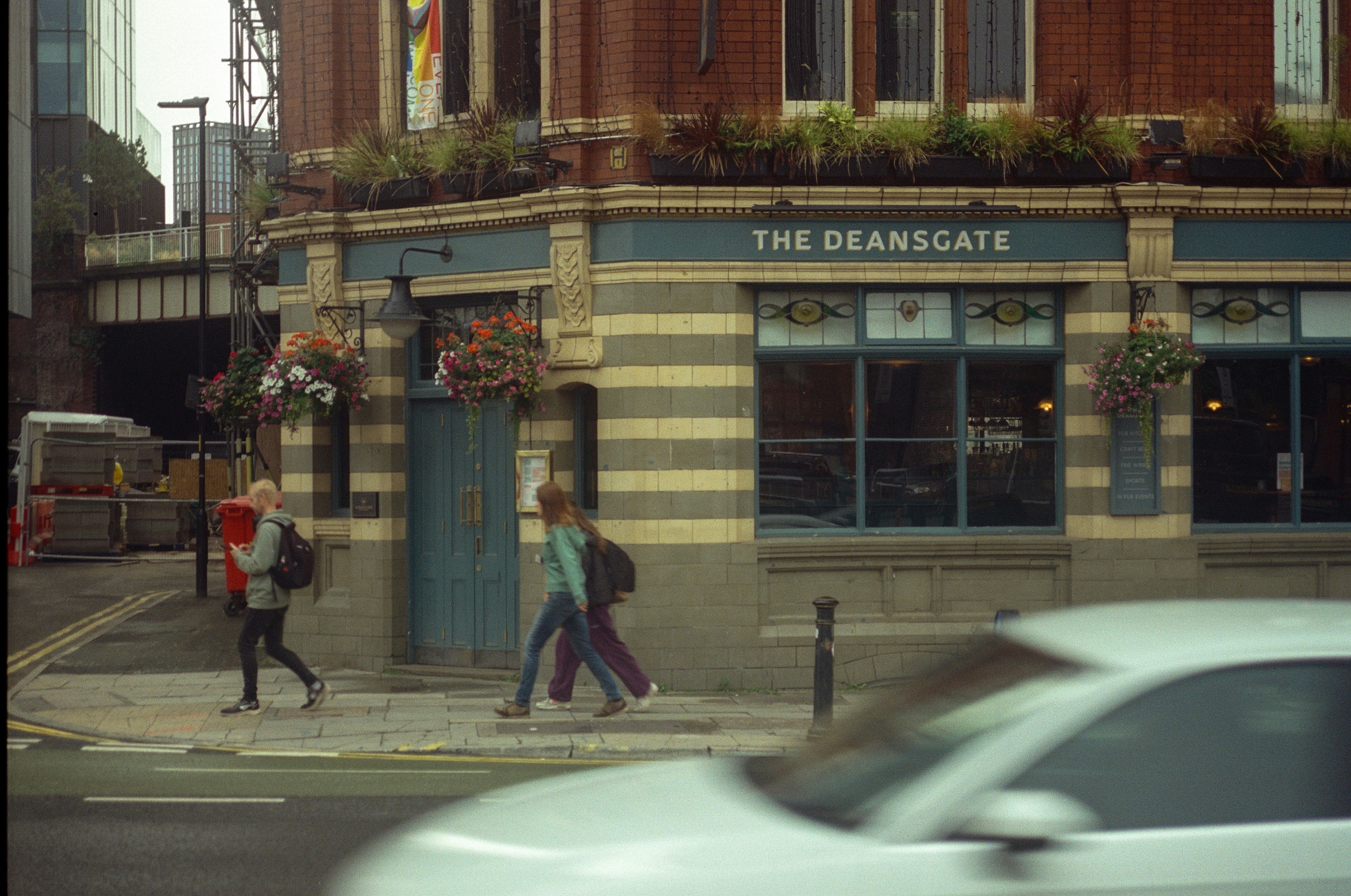 People walk past a pub called the deansgate.