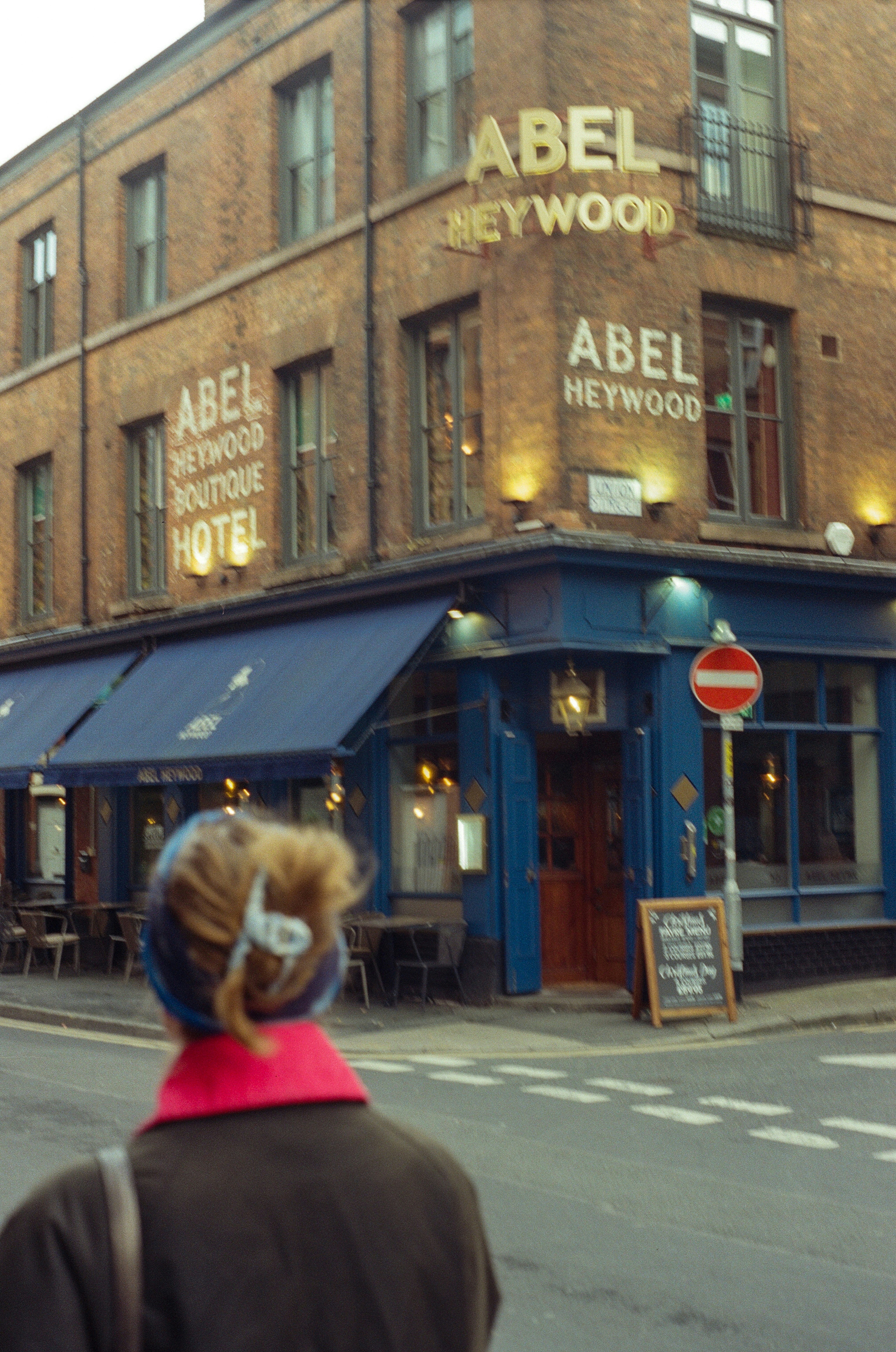 Woman walks past a boutique hotel on a street.