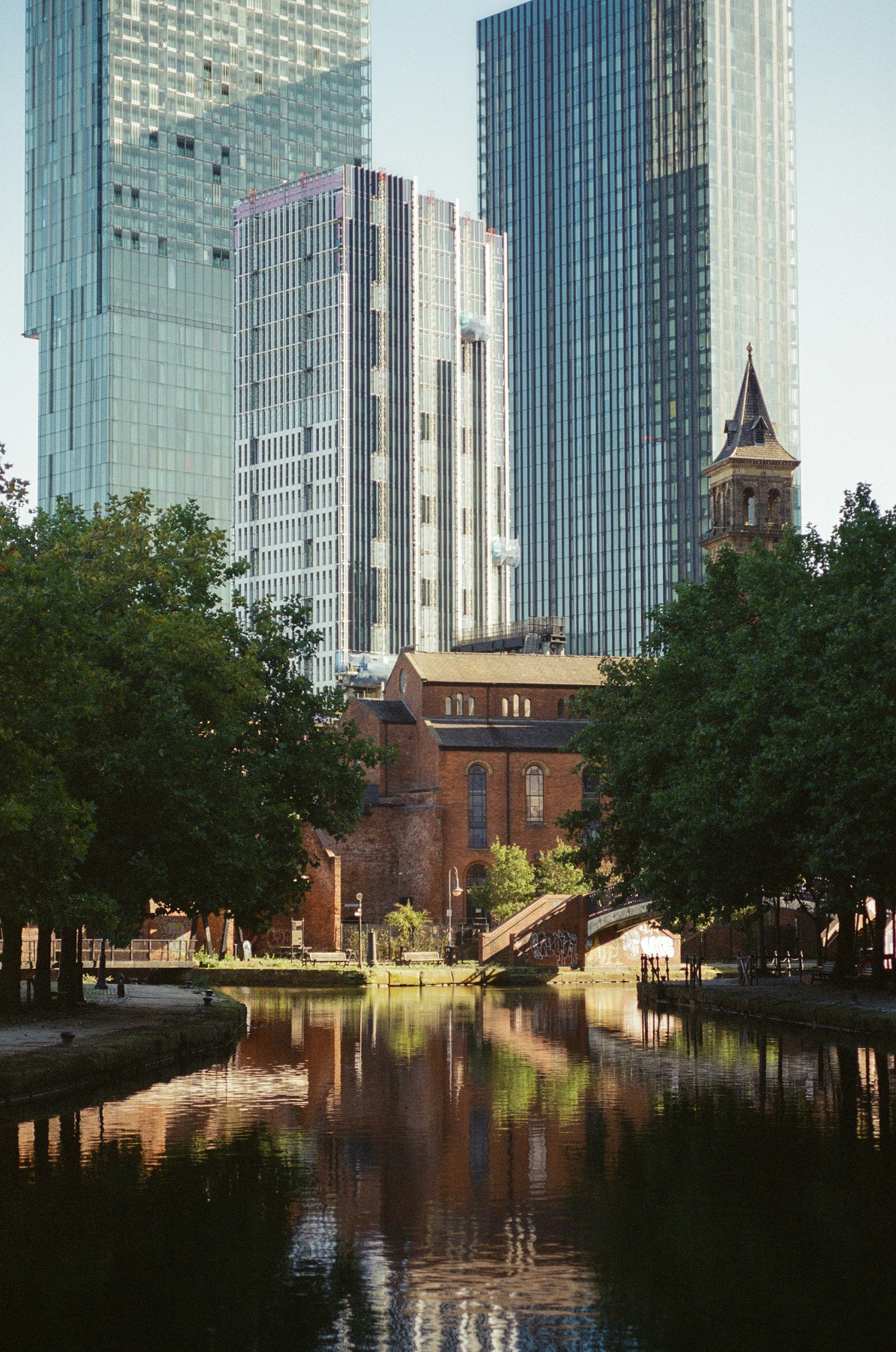 Modern skyscrapers overlook historic brick building by canal.