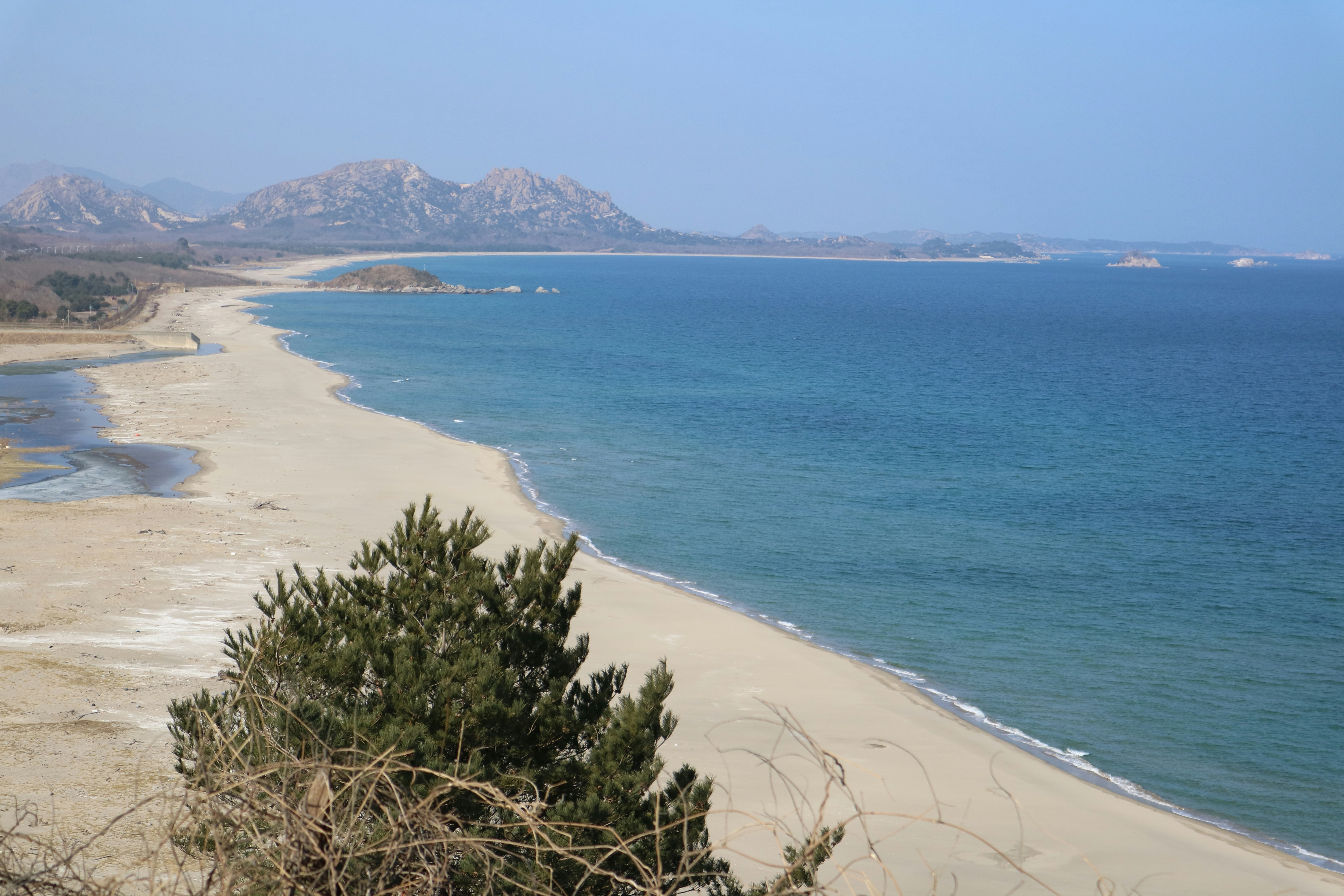 A long sandy beach meets the blue ocean.