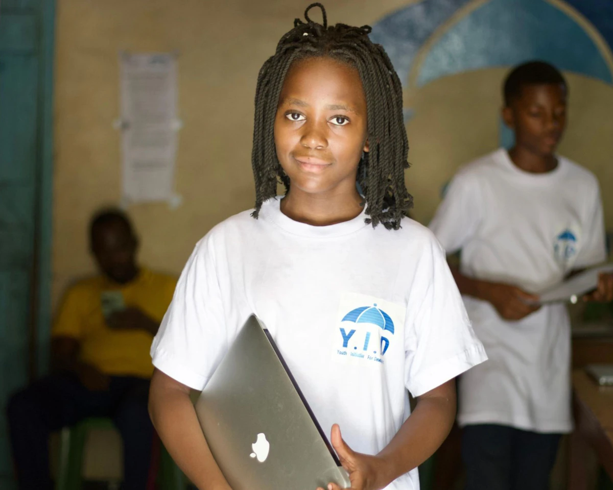 Student holding a laptop in a classroom