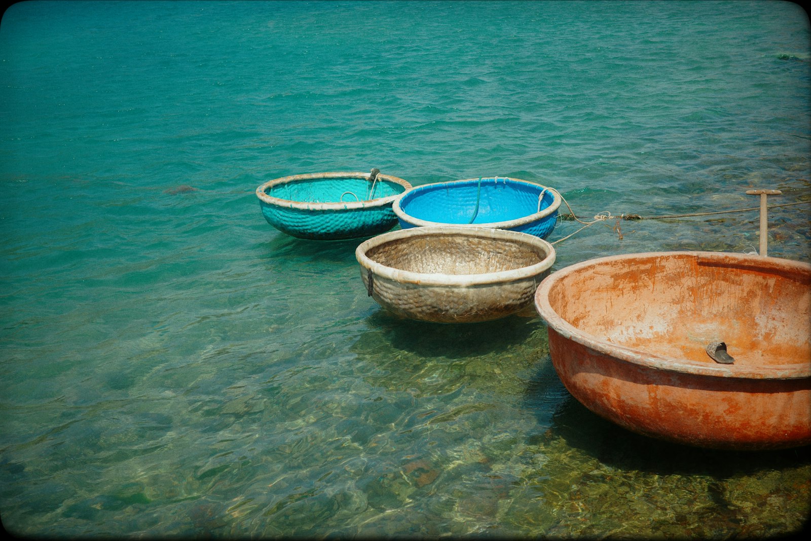 Four round woven-bamboo basket boats floating on clear blue-green water