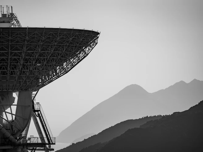 Large radio telescope dish with mountains in background