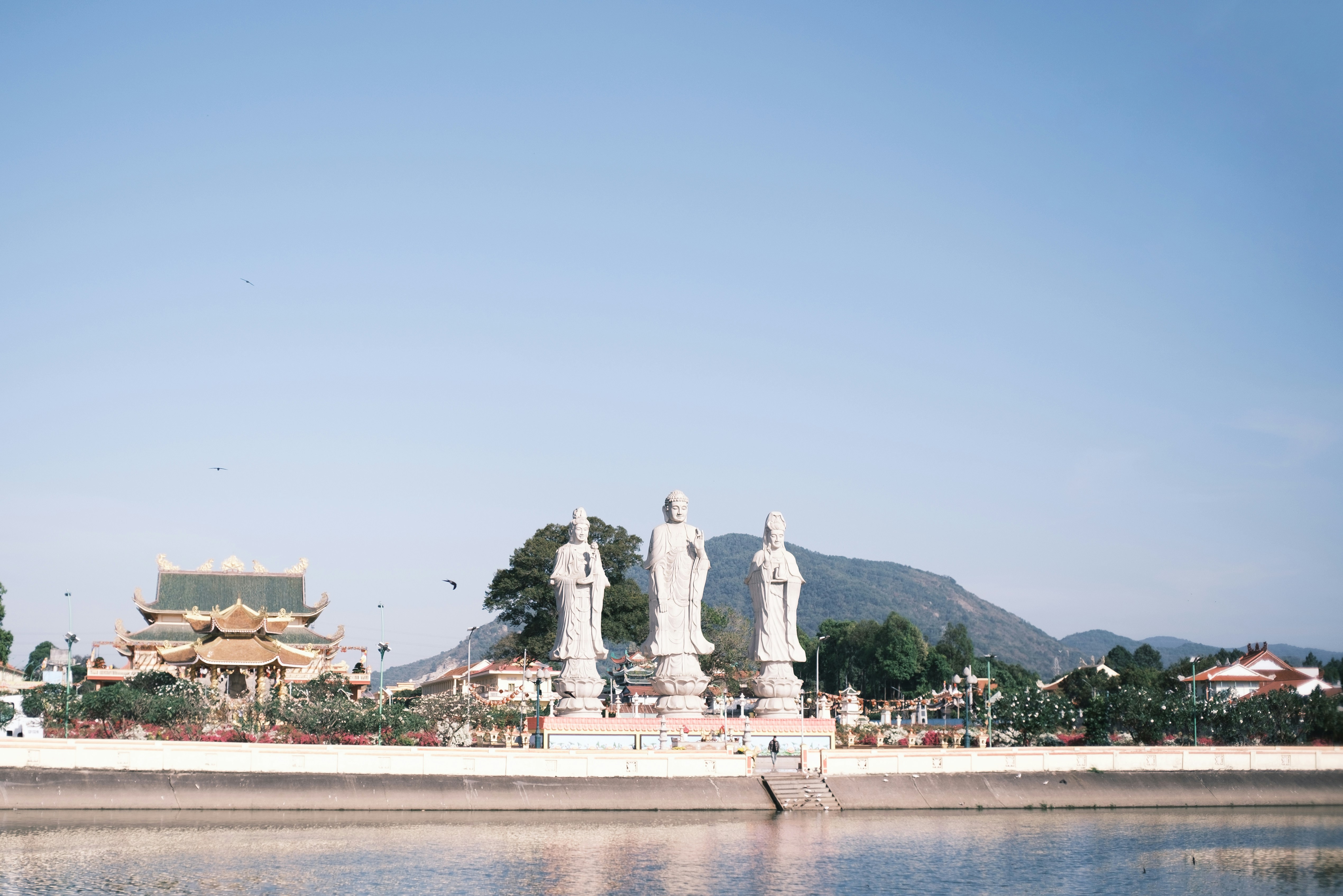 Three statues stand before a temple and mountain.