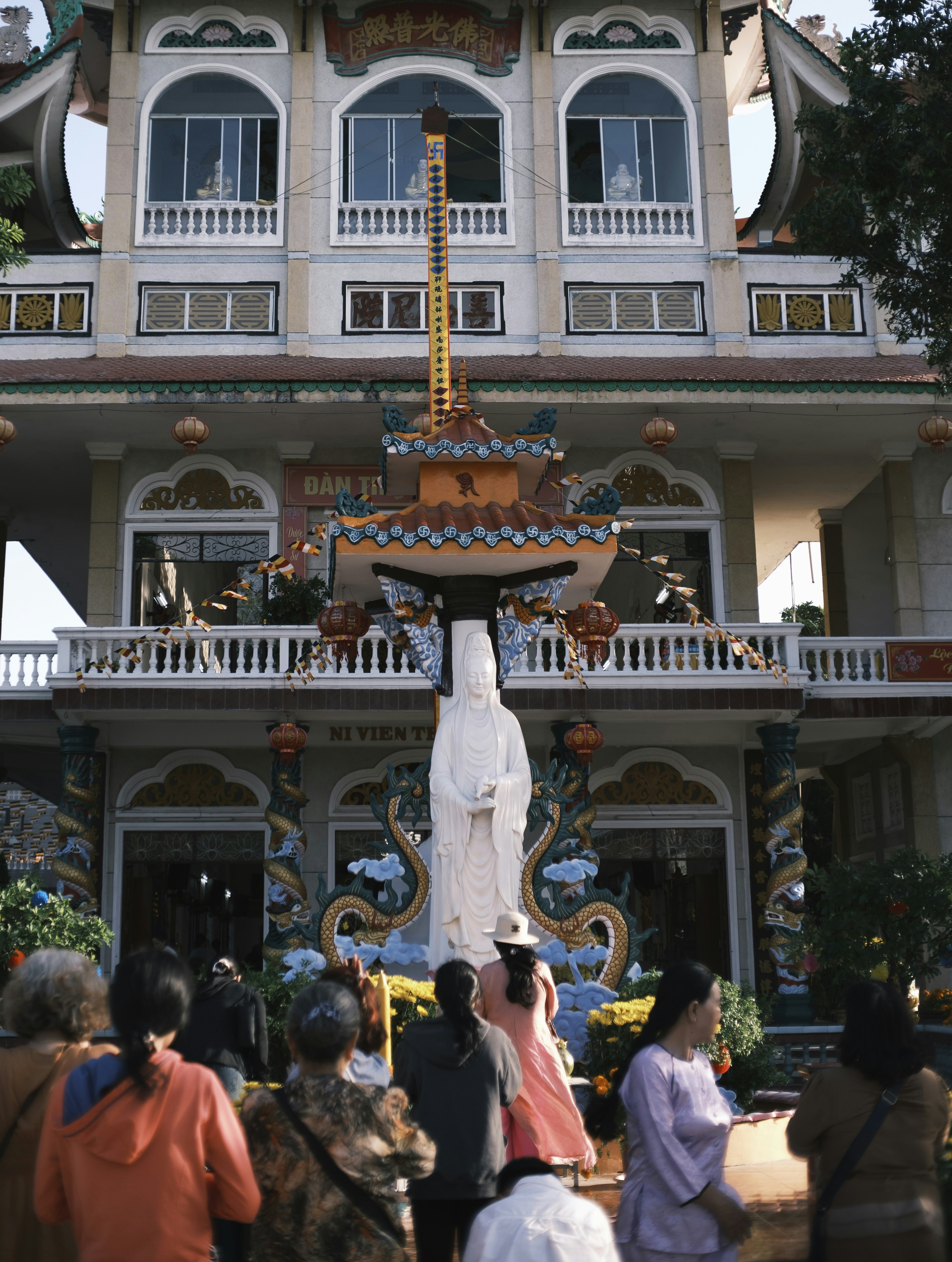 People gathered before a large white statue and temple.