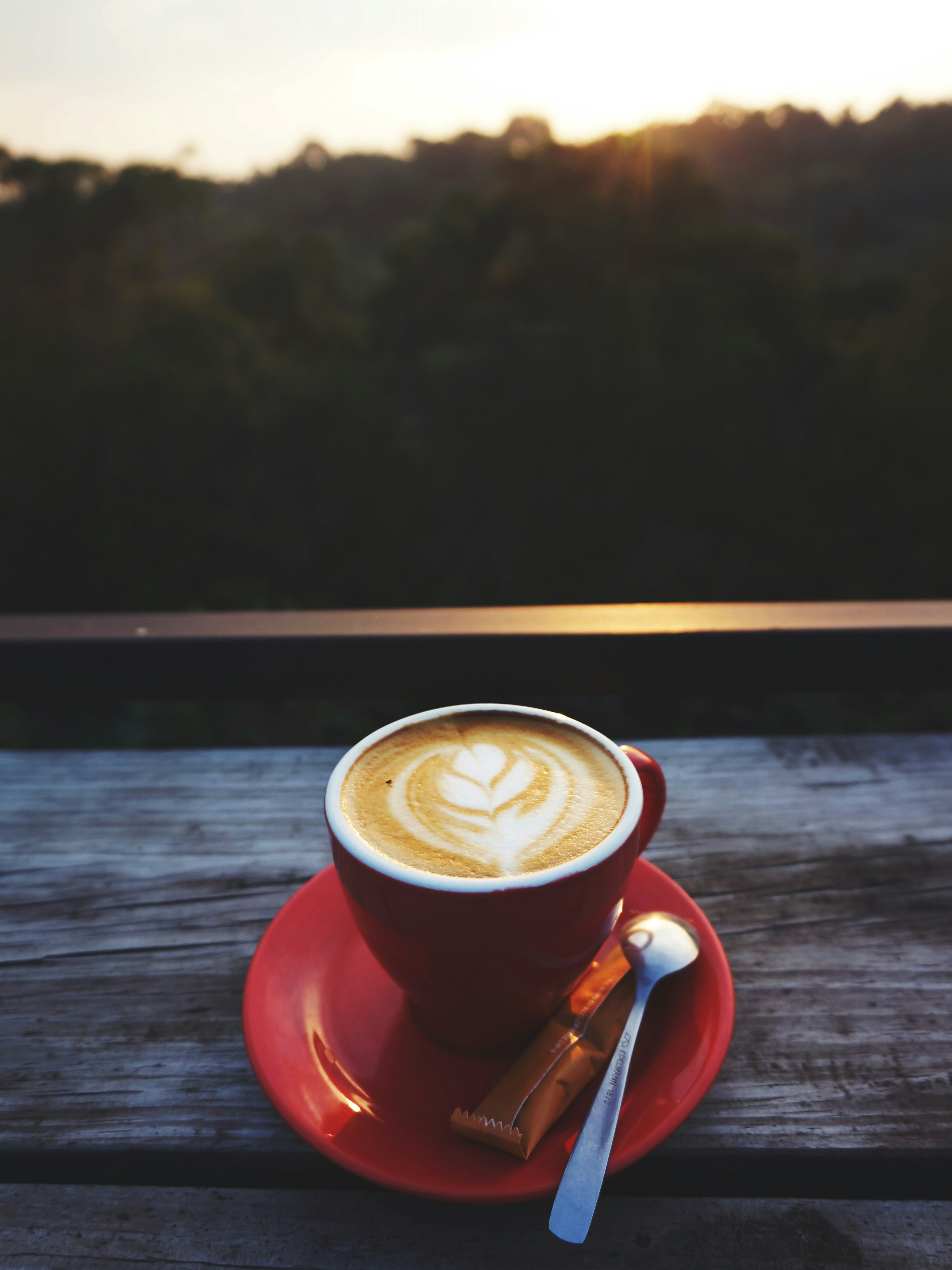 Secangkir kopi merah dengan latte art di atas meja kayu