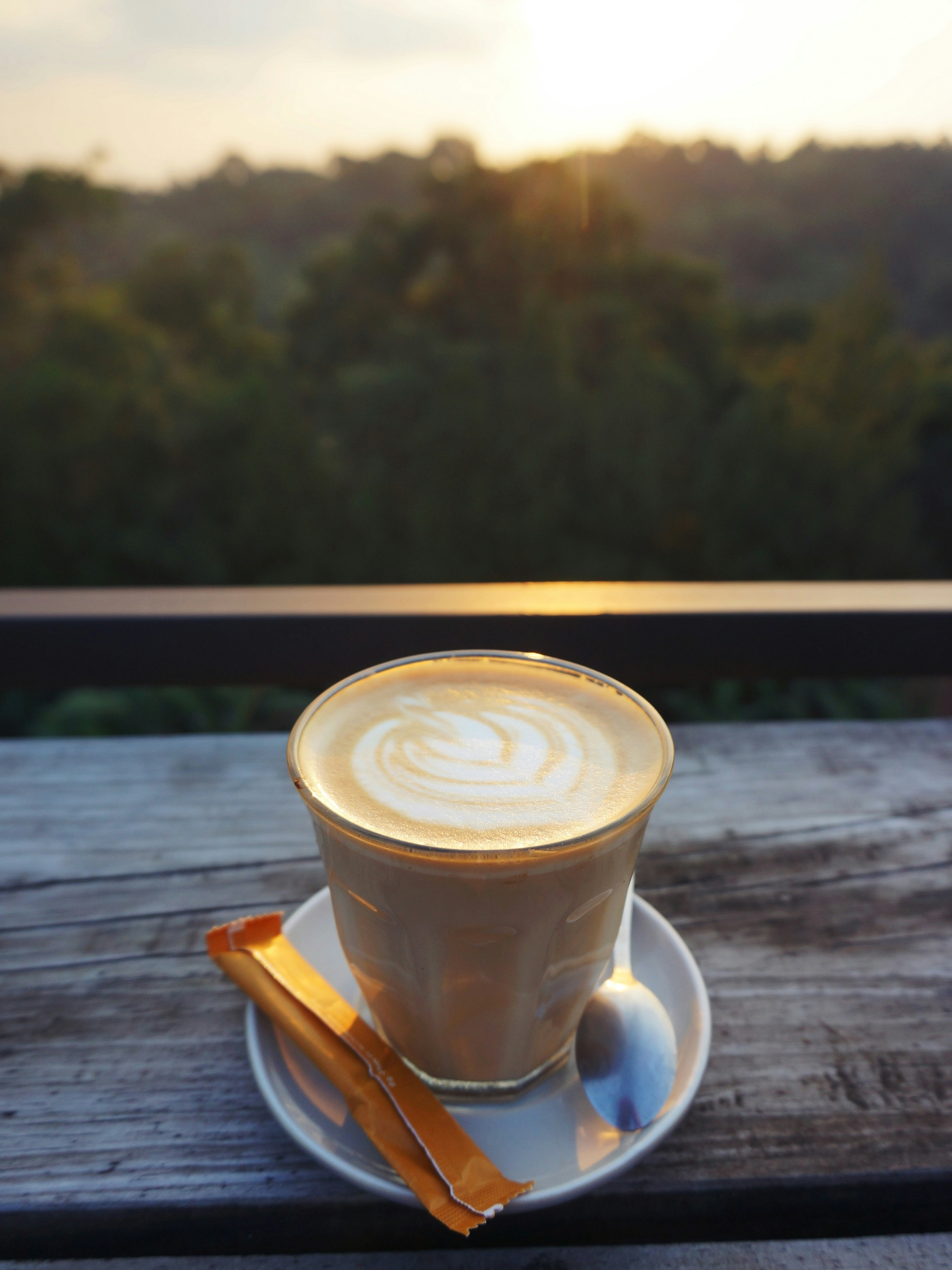 Latte dengan seni busa duduk di atas meja kayu.