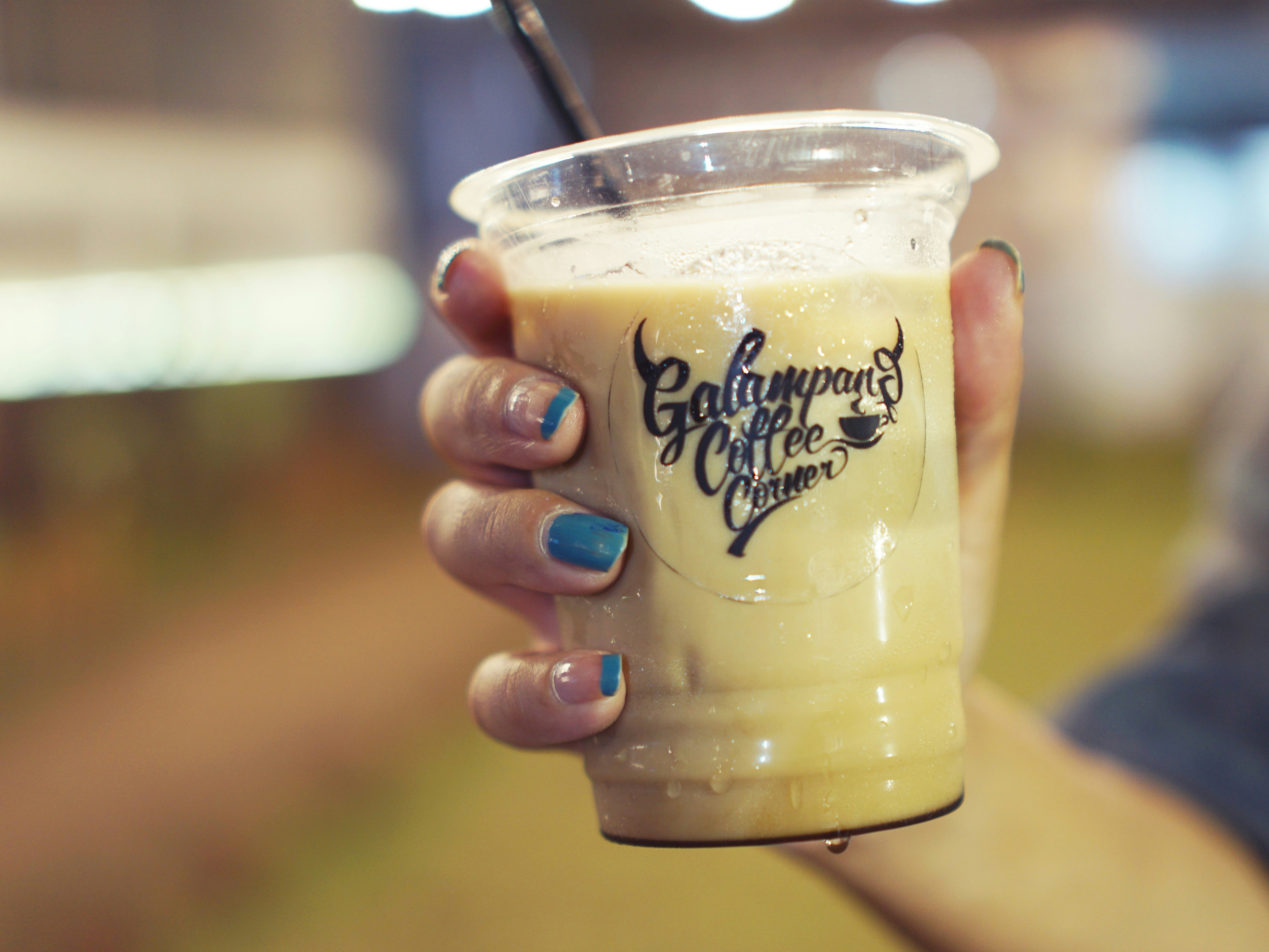 Tangan memegang minuman kopi dingin dengan sedotan