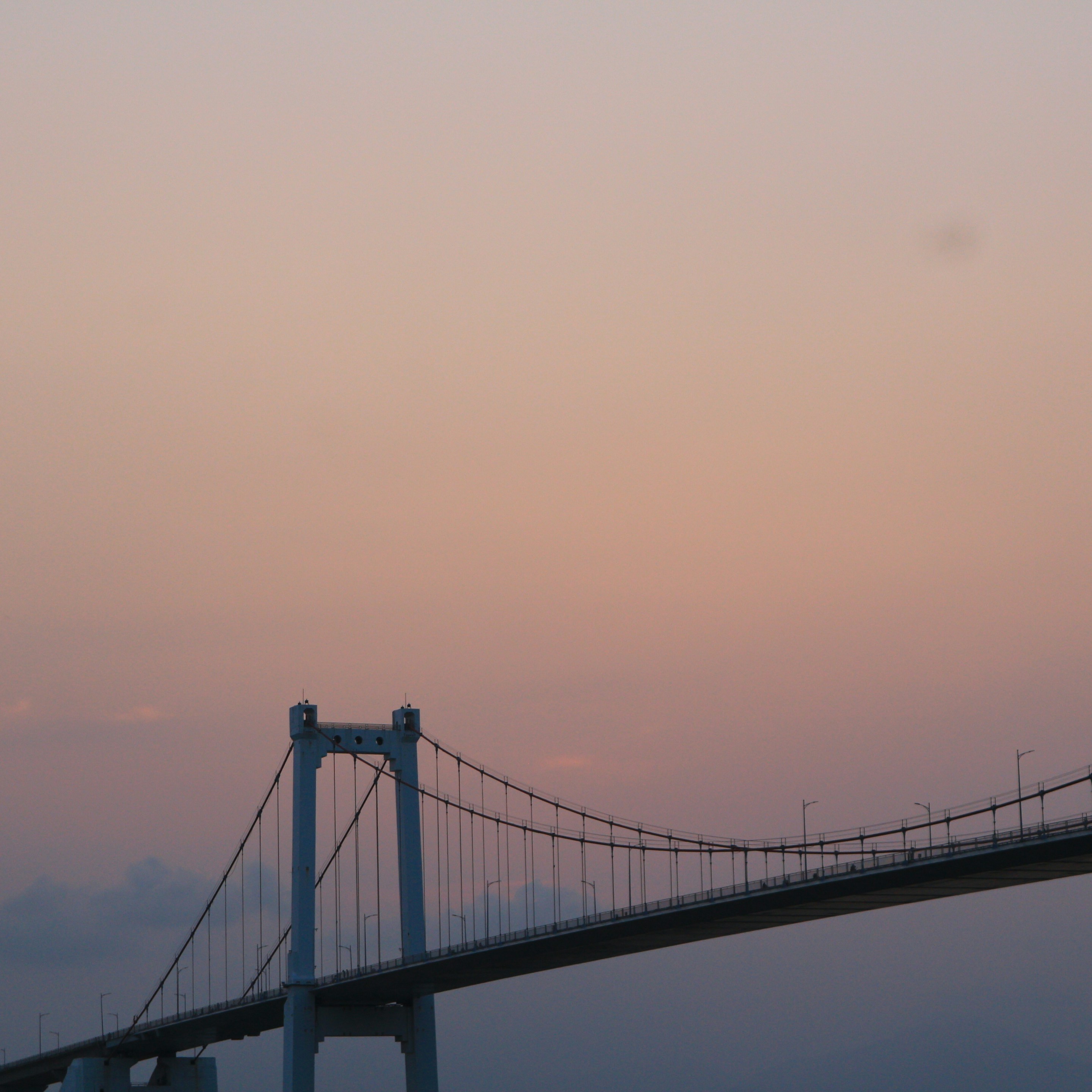 Suspension bridge against a soft pastel sky.