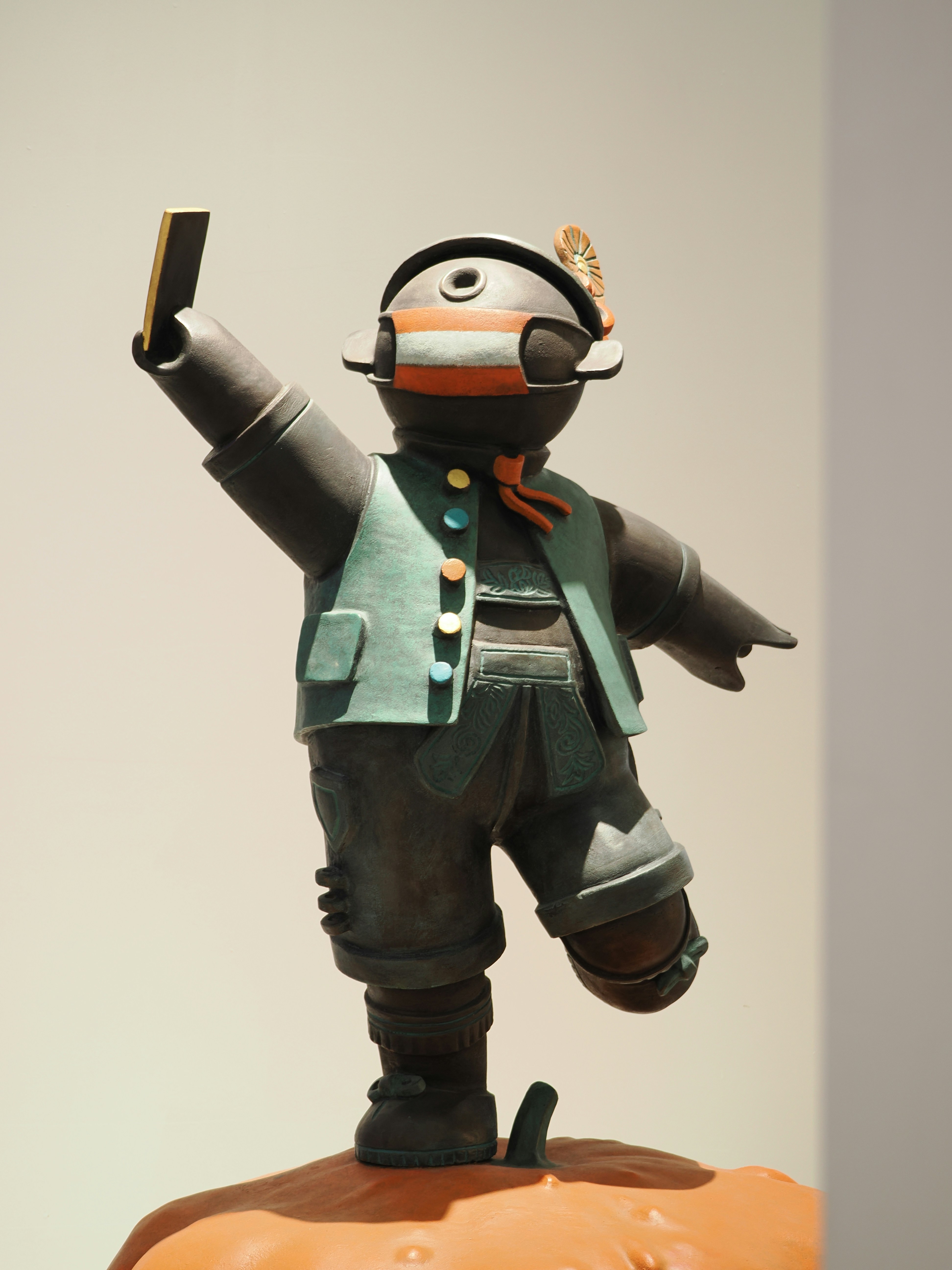 A bronze figurine taking a selfie with a smartphone.