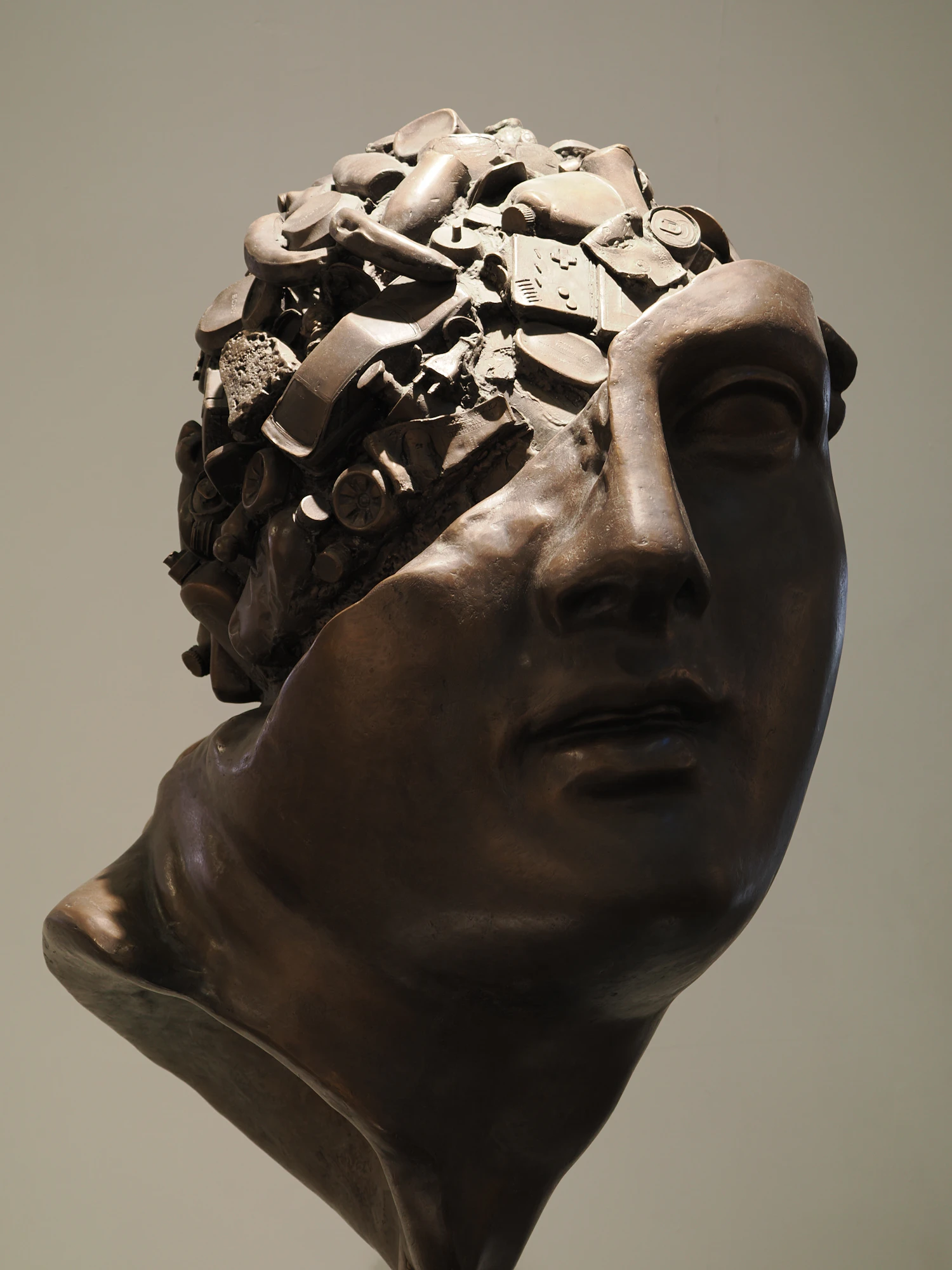 A bronze head cast with a fragmented, broken surface across the brow