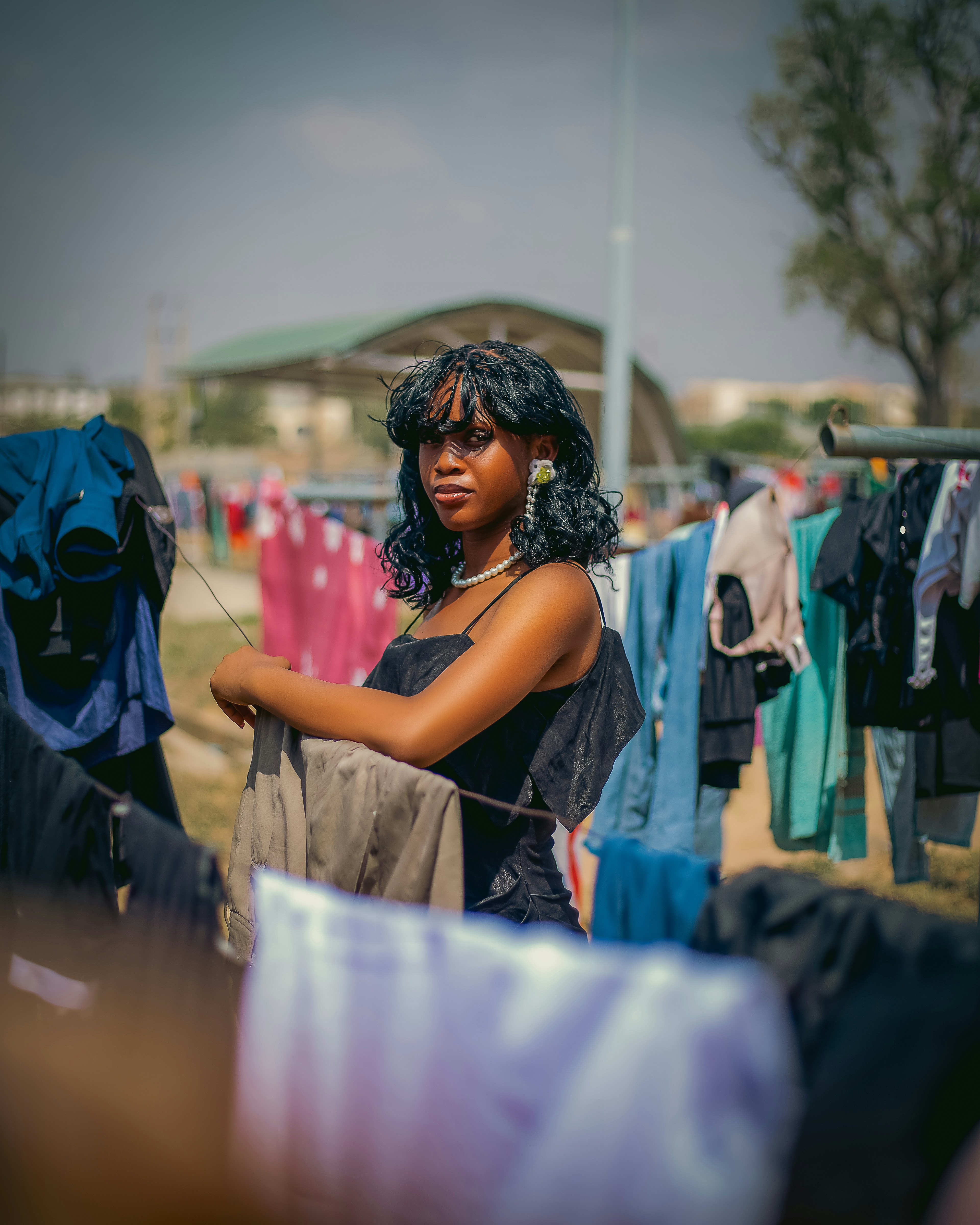 Una giovane donna sta tra i vestiti appesi agli appendiabiti