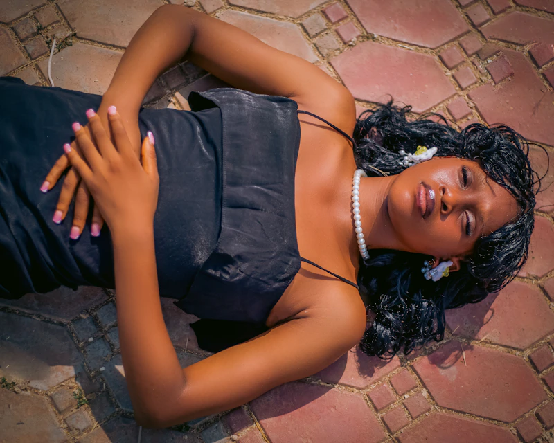 woman in a black dress lying on patterned ground