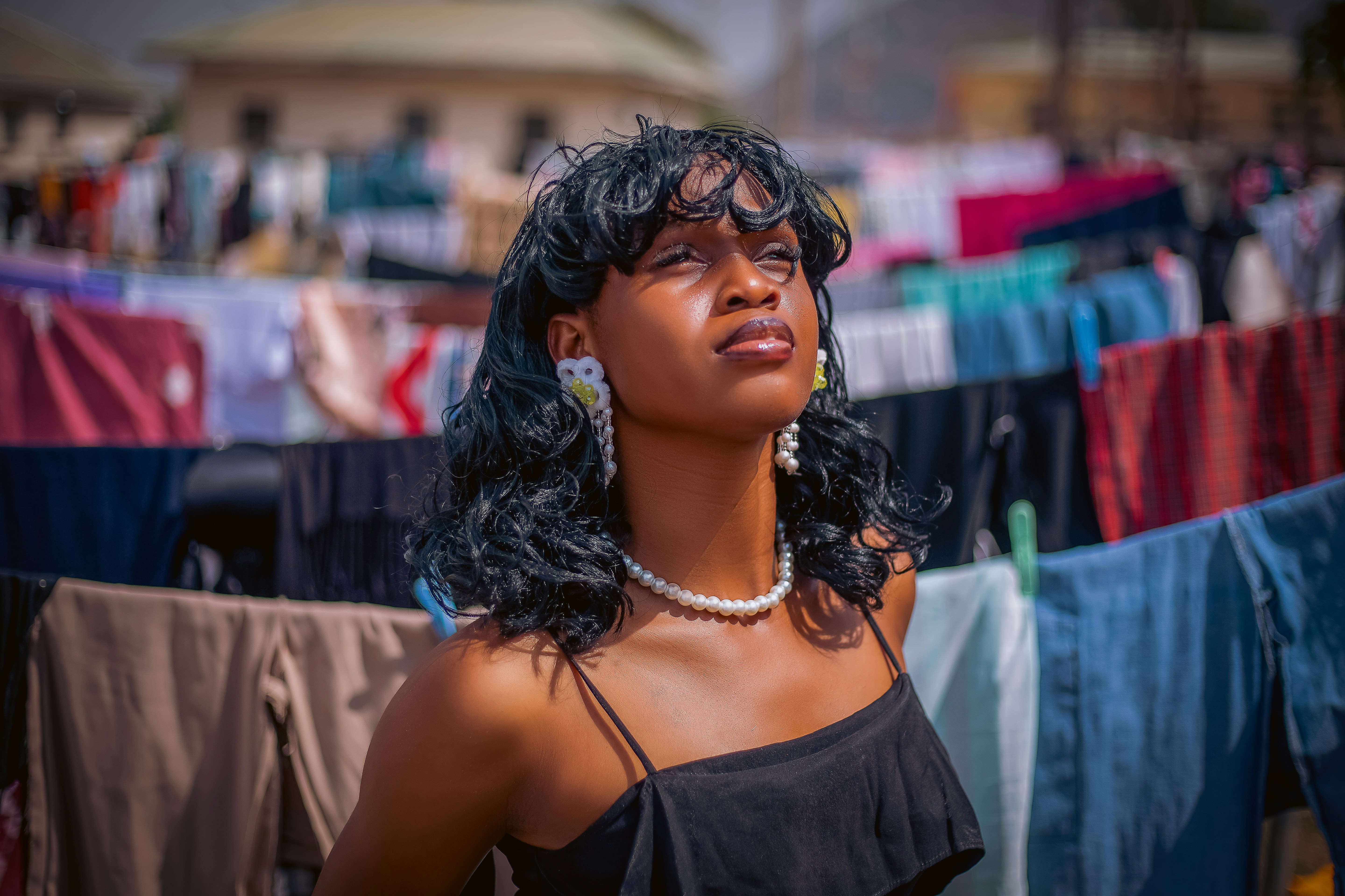 Giovane donna con capelli scuri e ricci e collana di perle