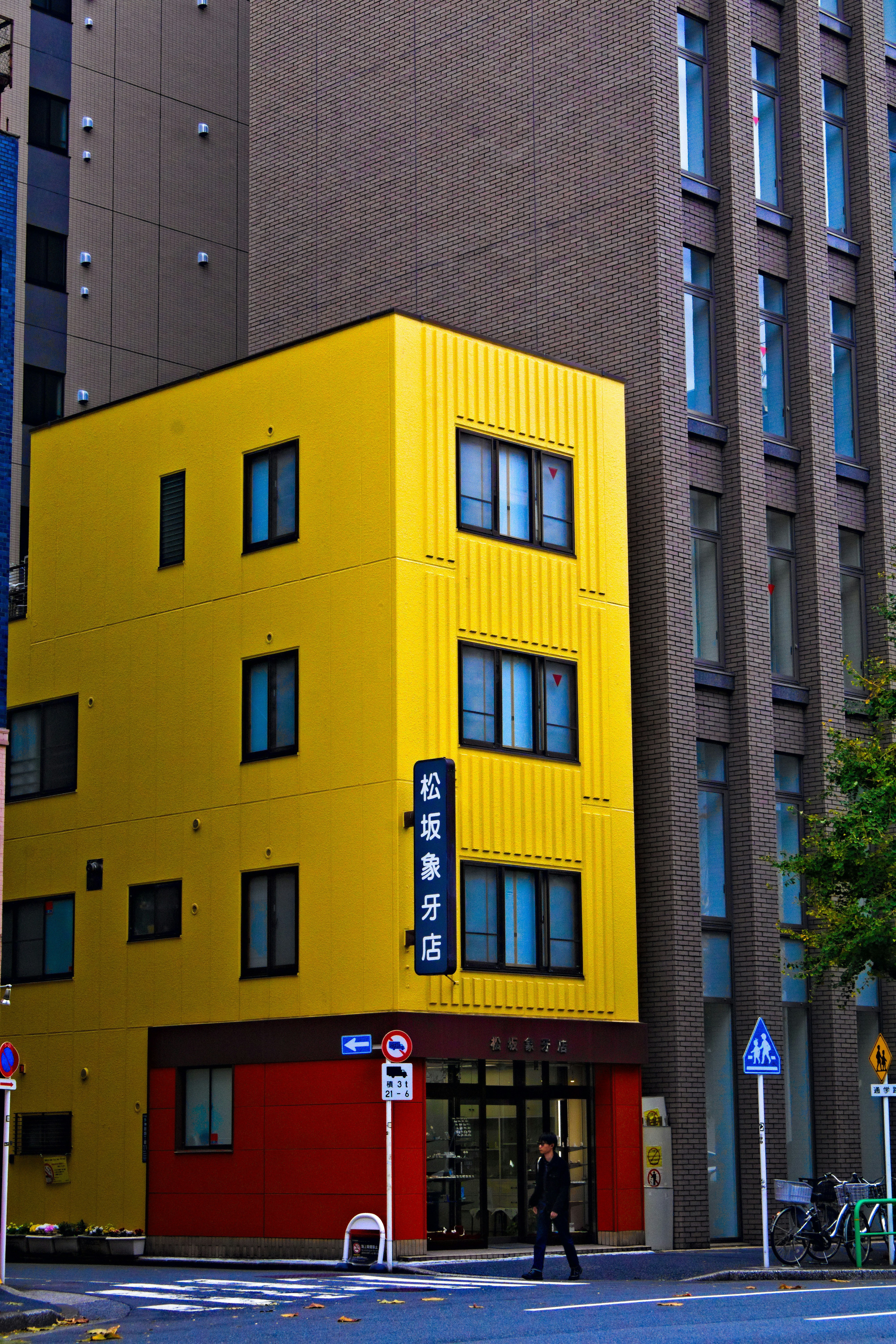 A bright yellow building with red base in city