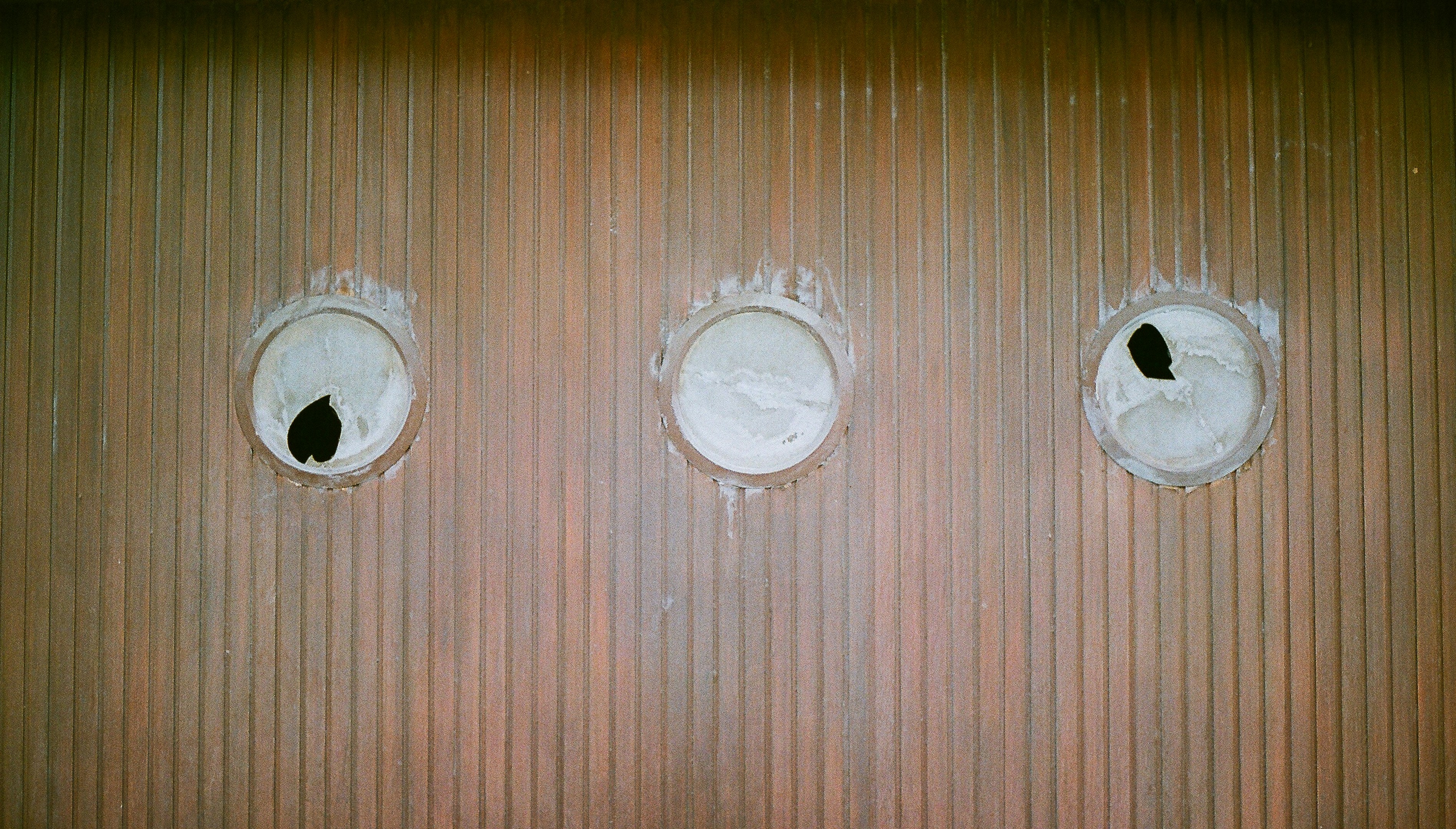 Three circular holes in a textured wall.