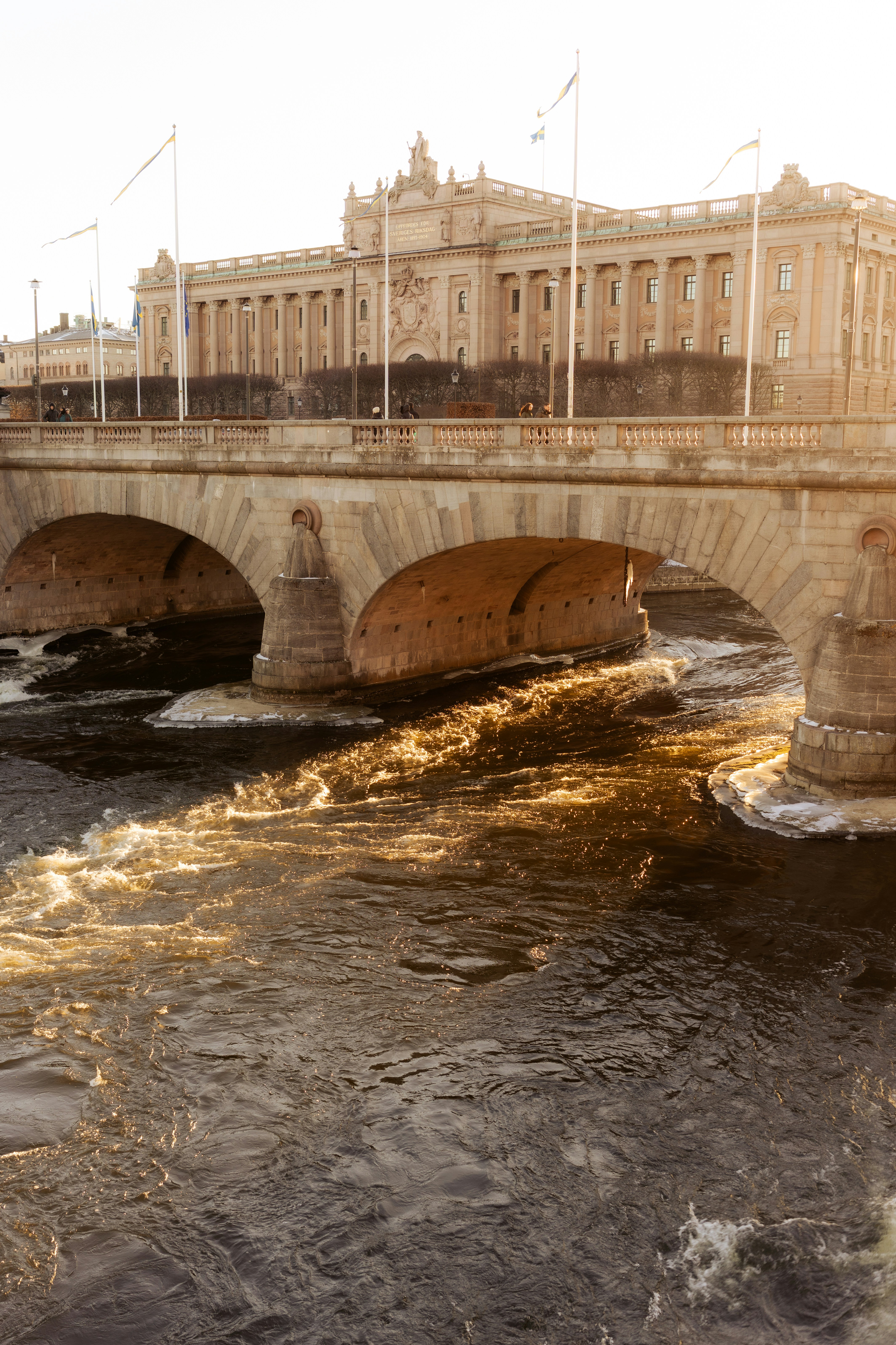 강 위에 있는 돌다리와 그 뒤에 큰 건물이 있습니다