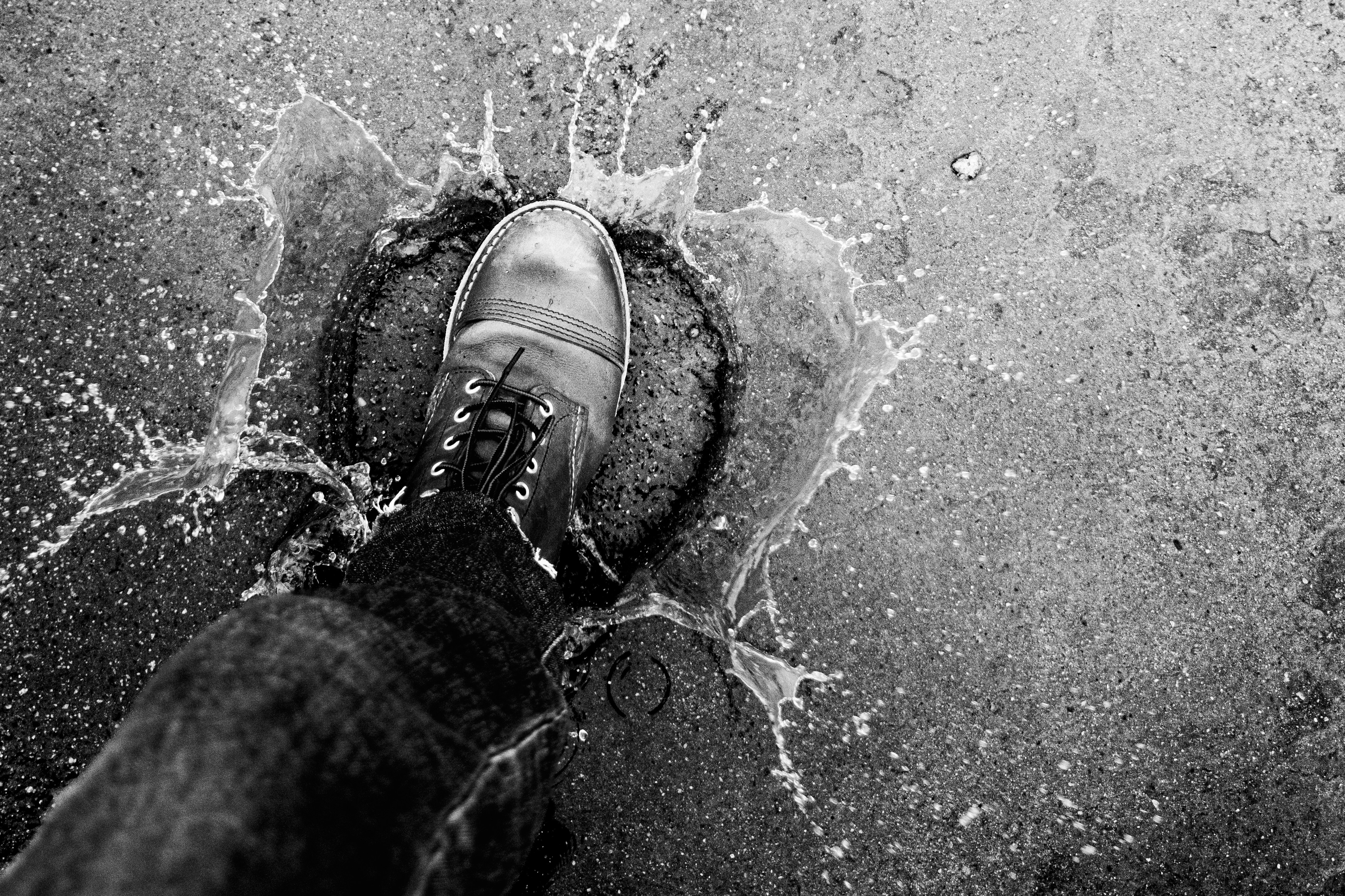 Ein Stiefel spritzt Wasser auf eine strukturierte Oberfläche.