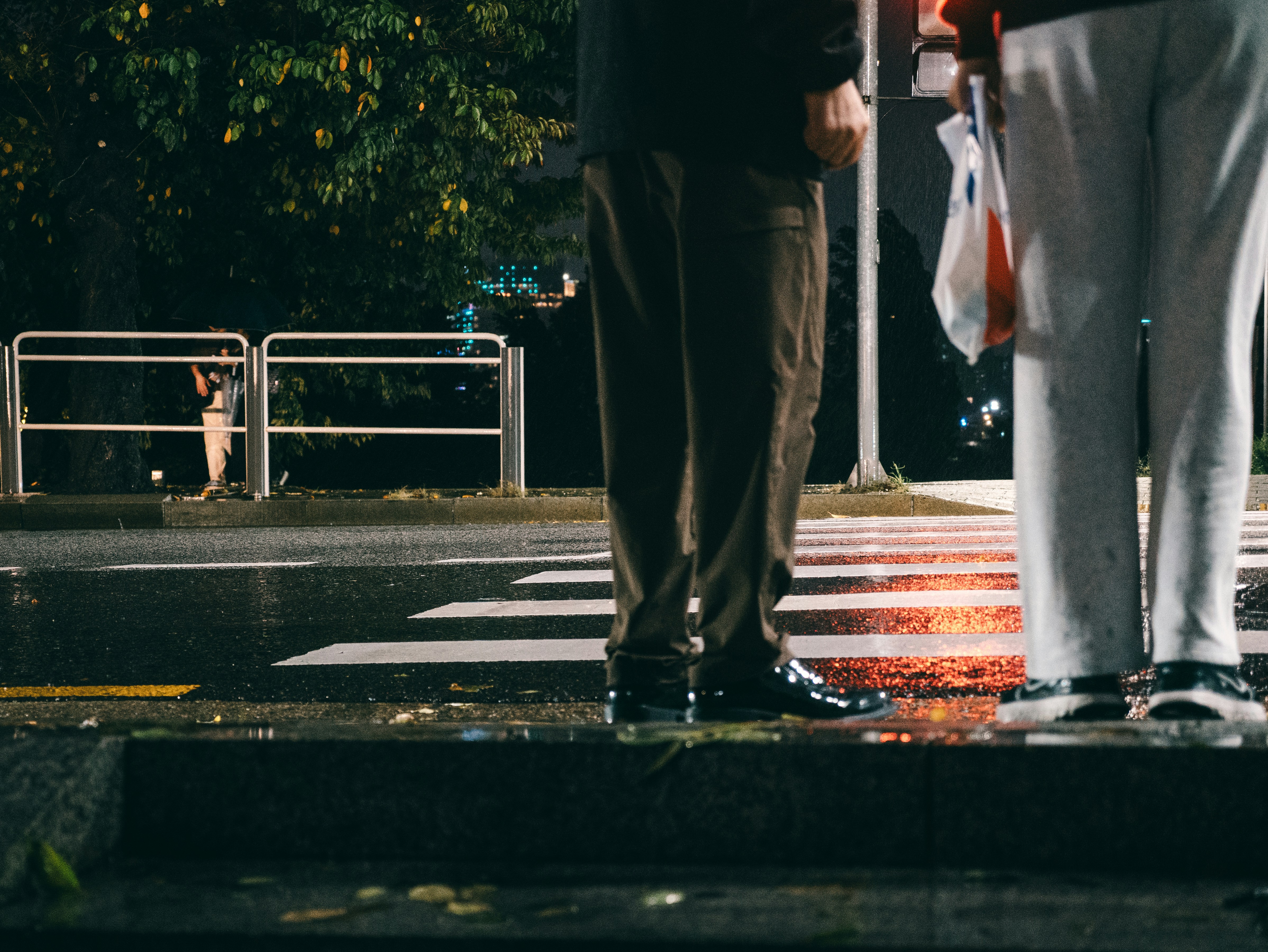 Zwei Menschen stehen nachts auf einer nassen Straße.