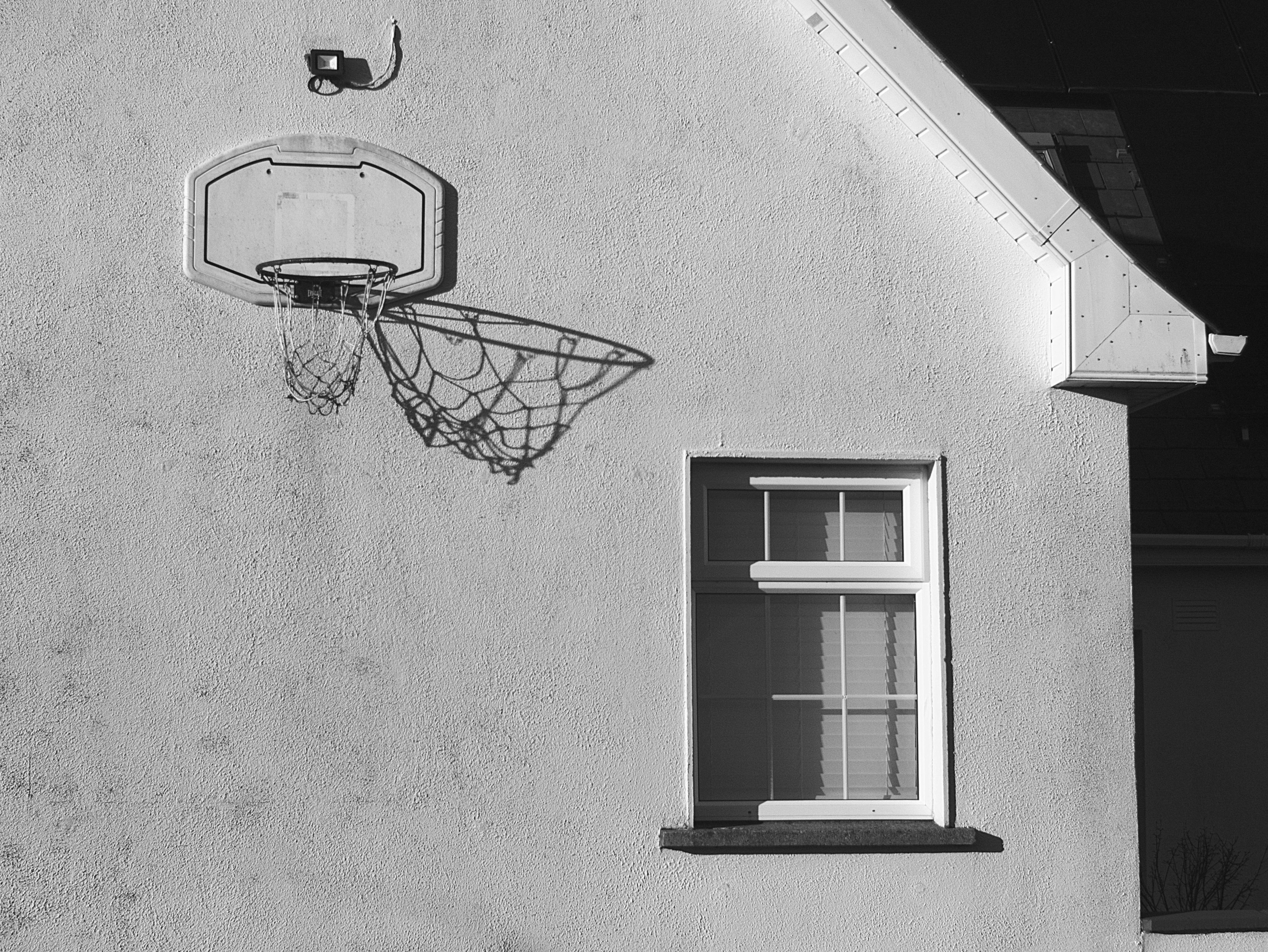 Basketball hoop mounted on a white wall next to window