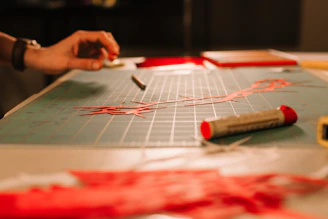 Hand working on red threads and tools on mat