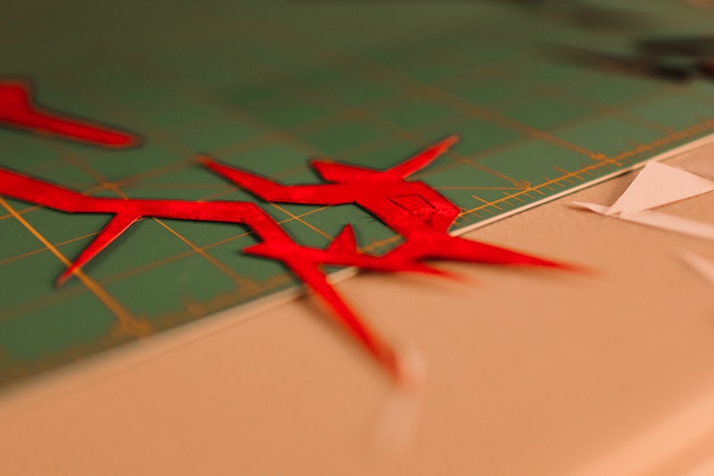 Red abstract shapes on a green cutting mat.