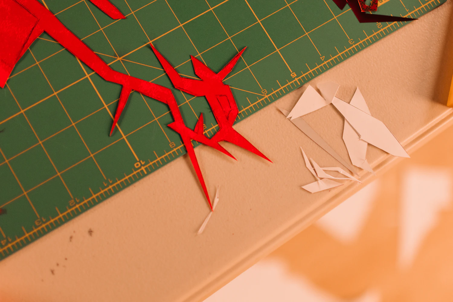 Red paper cut-outs and offcuts lying on a green cutting mat