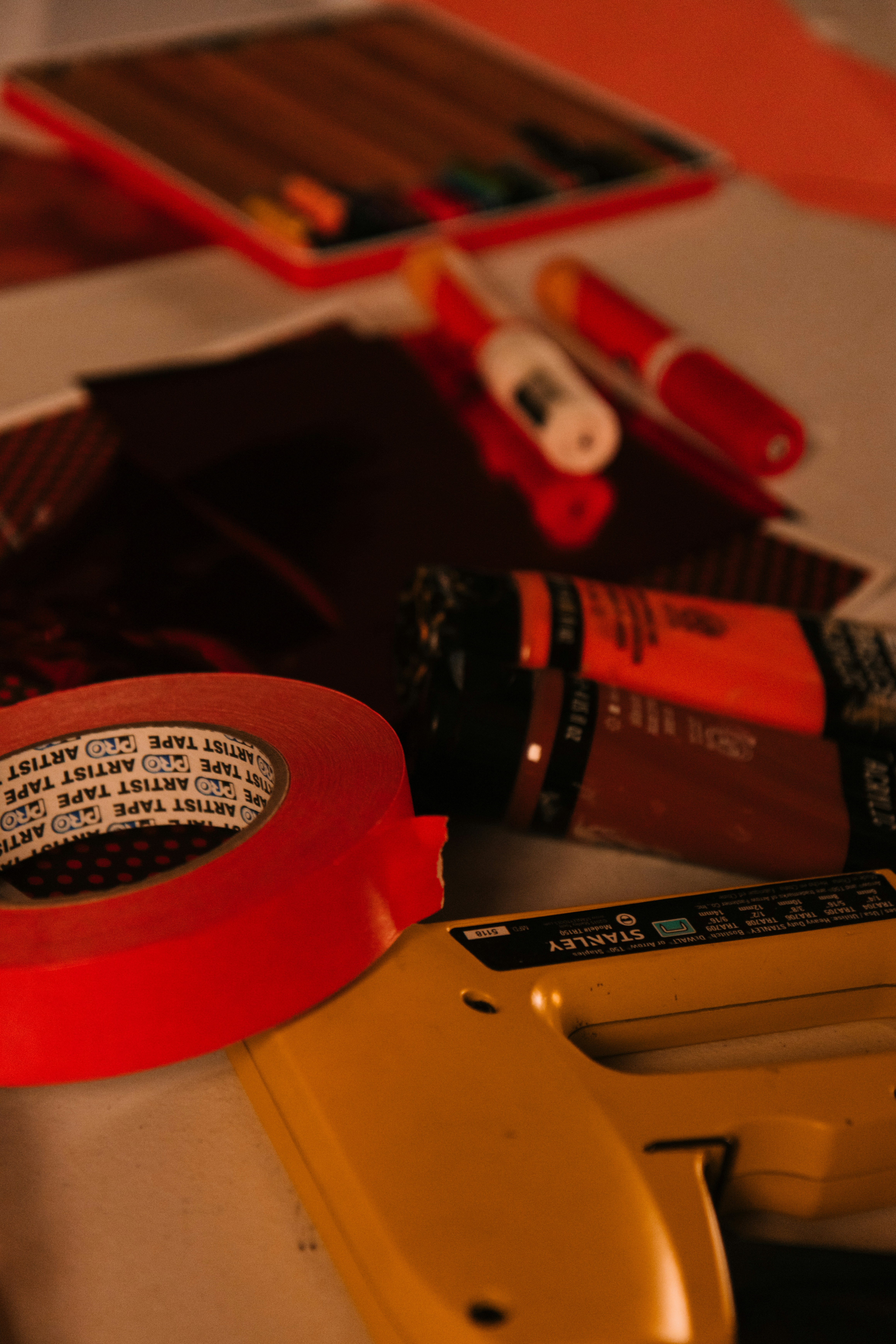 Art supplies including tape, stapler, and paint tubes.