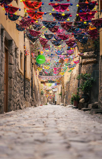 Narrow cobblestone street decorated with colorful flags and vibrant banners.