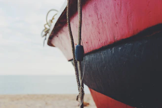 Close-up of a red and black boat on a beach