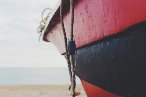 Close-up of a red and black boat on a beach