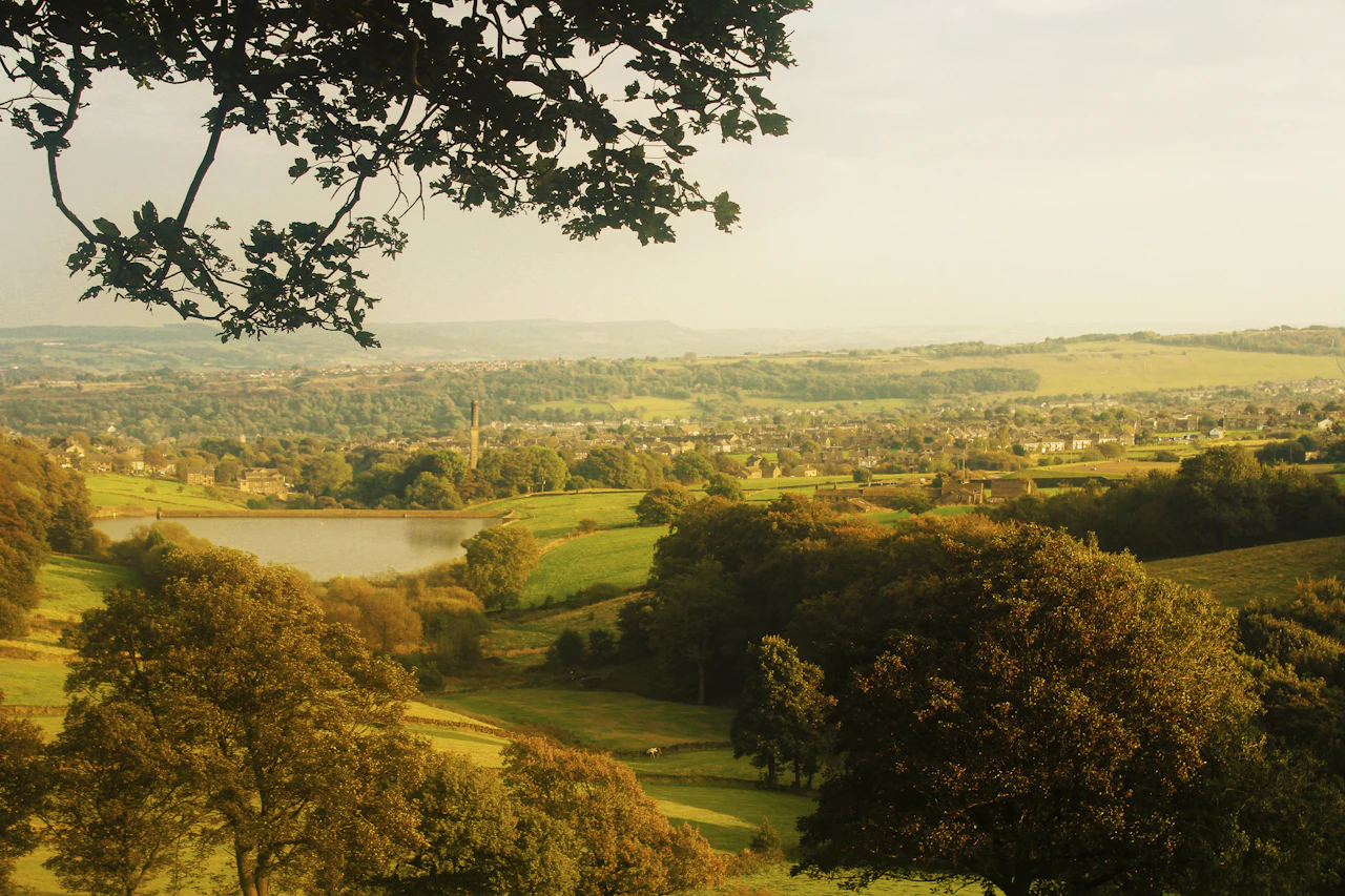 Rolling green hills with a distant village and lake