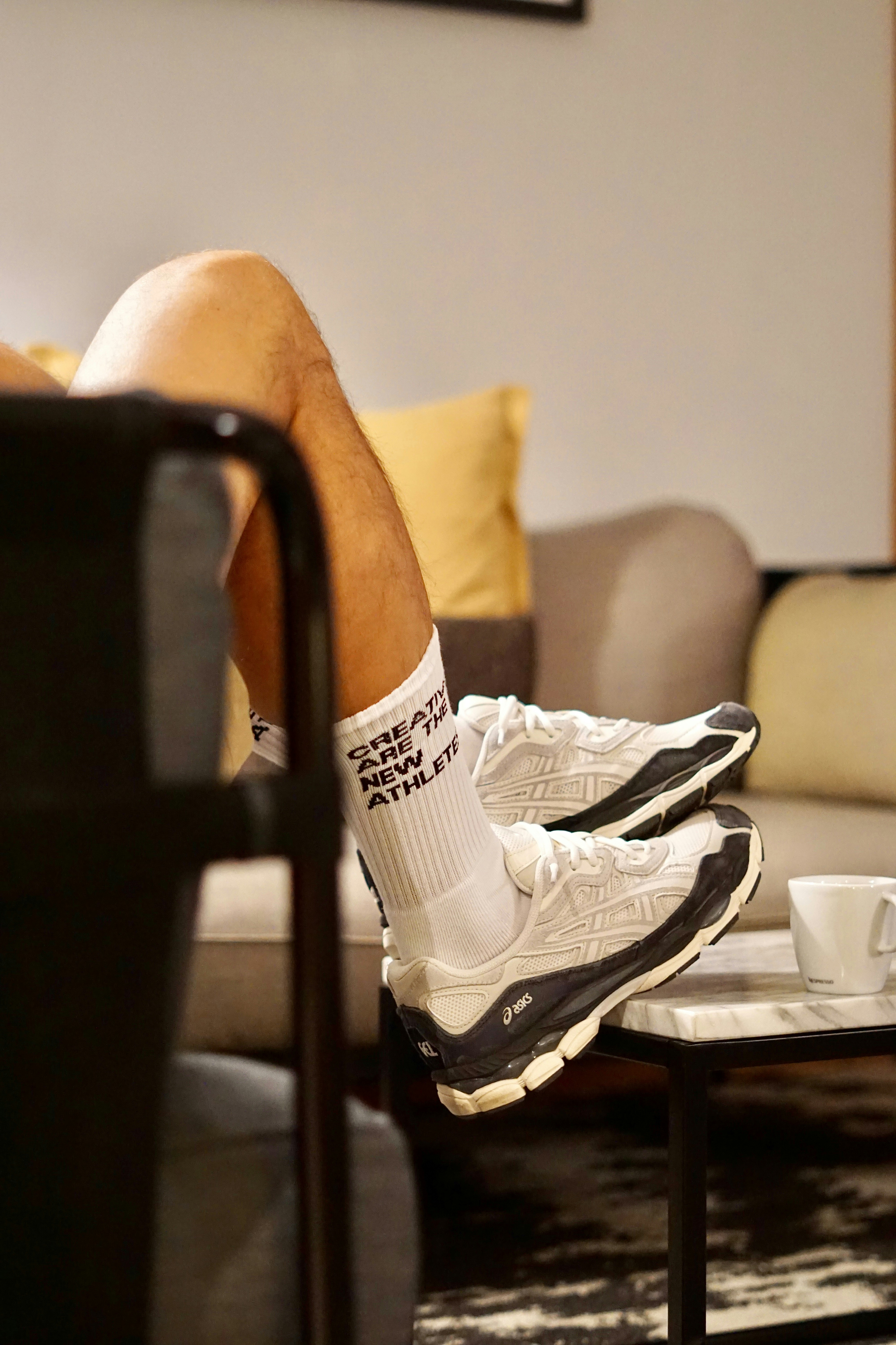 Person's legs wearing white socks and sneakers resting.