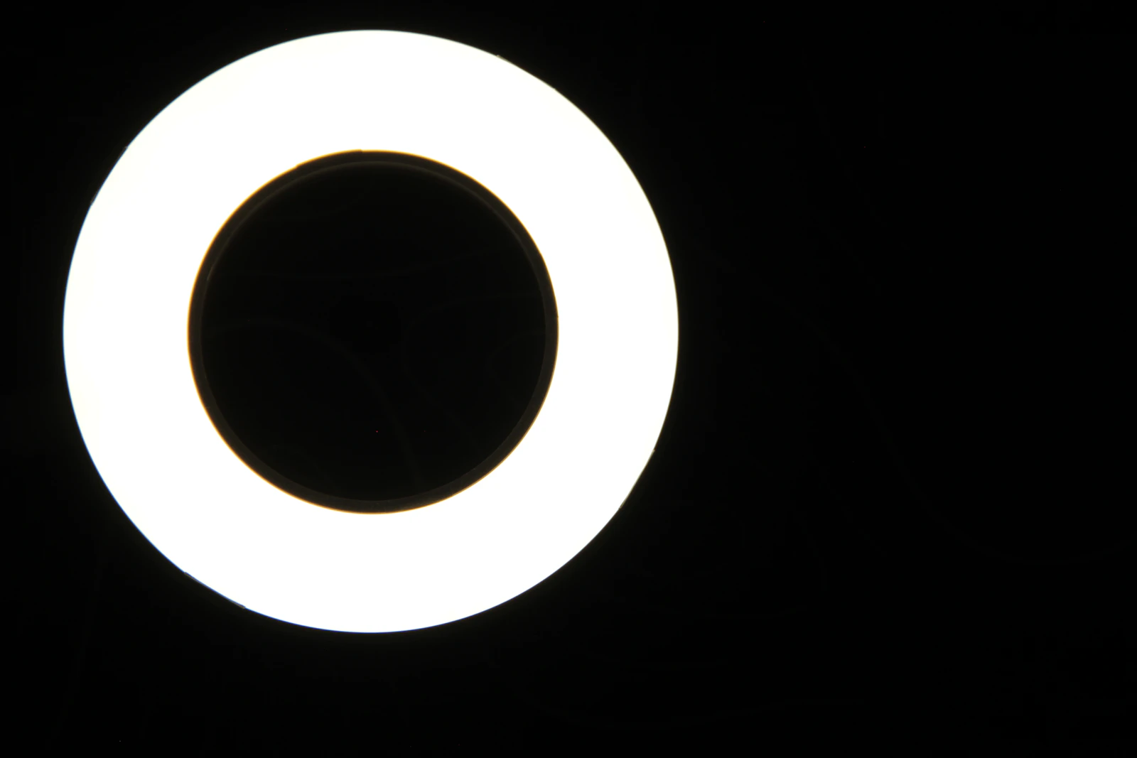Glowing white circular ring light against a black studio backdrop.